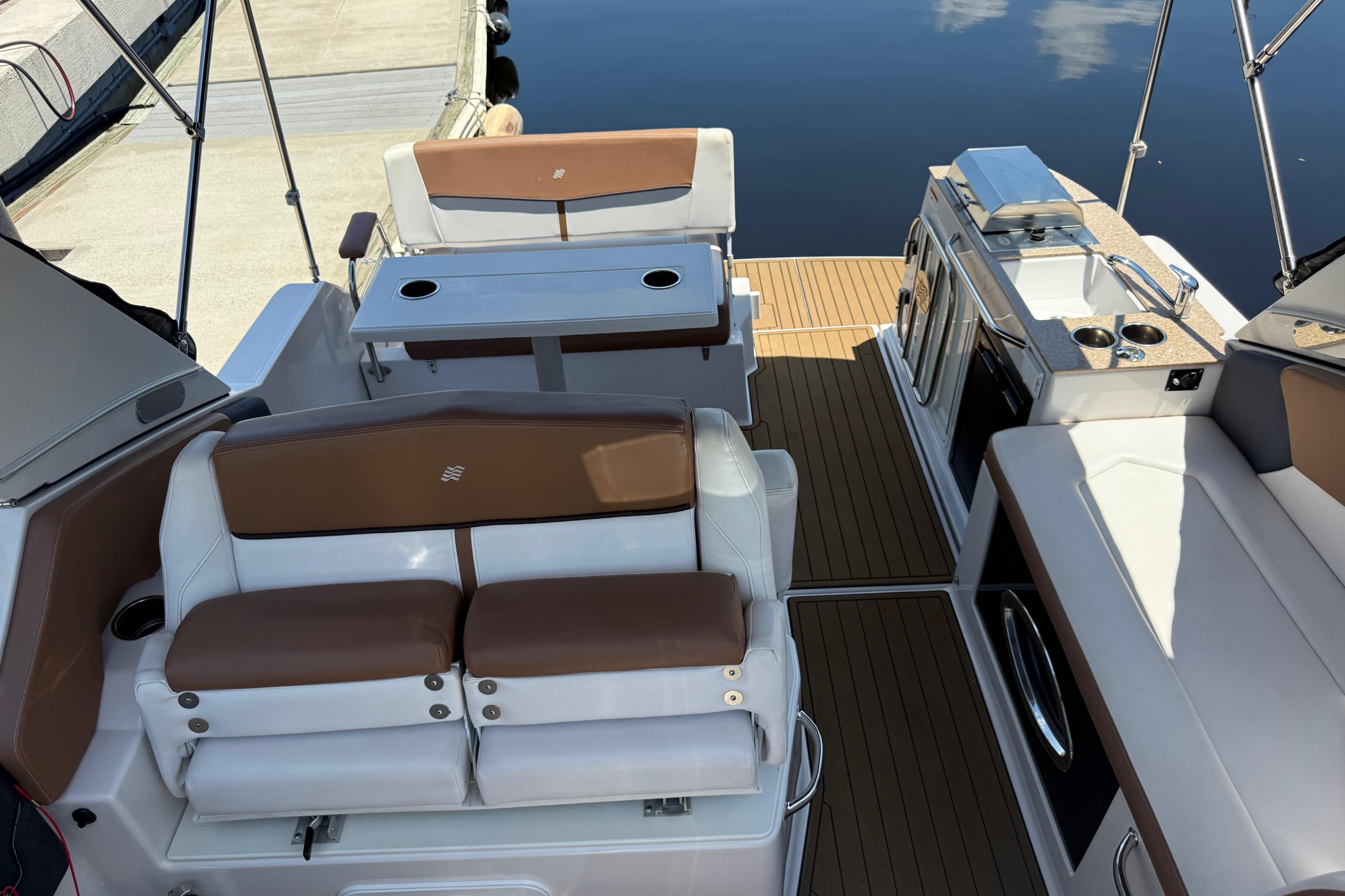 2017 Four Winns V275 boat interior with seating, table, and kitchenette by the water.