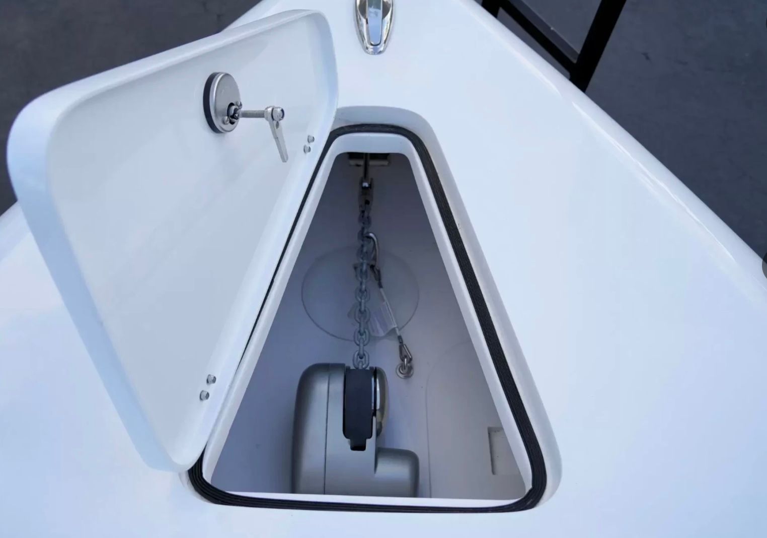 An open storage compartment on a boat with a chain and anchor inside.