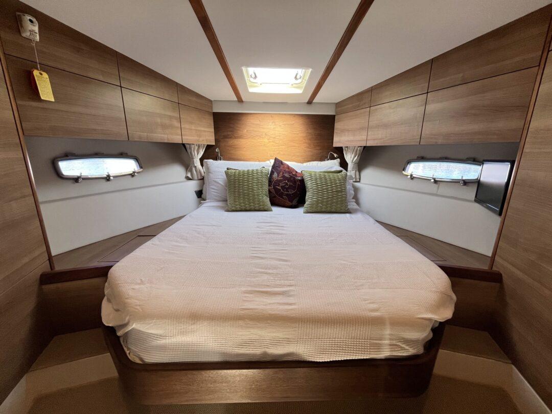 Luxurious cabin interior of 2012 Sealine SC 47 yacht with cozy bed and wooden finish.