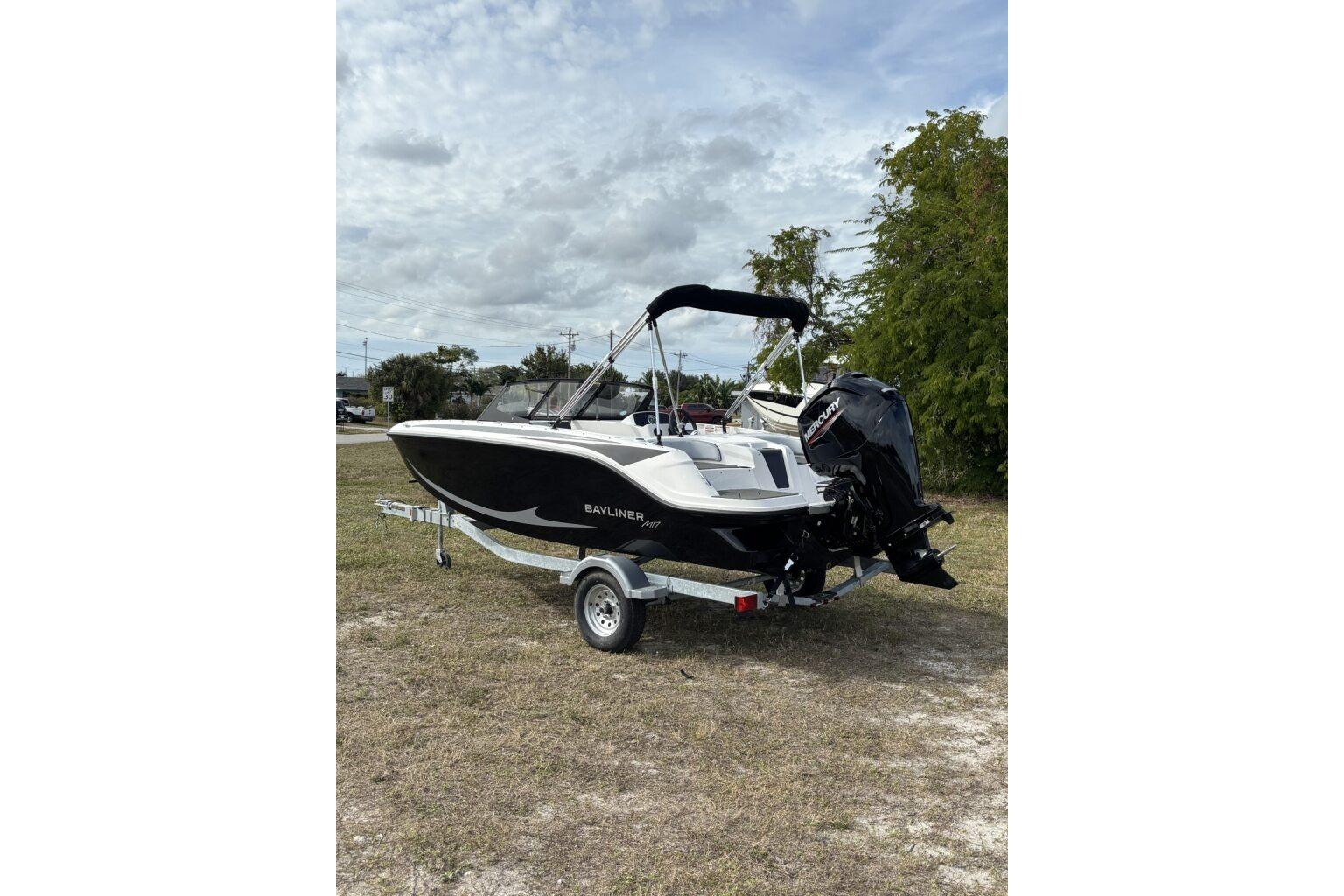 2025 Bayliner Element M17 boat on trailer, parked on grass under cloudy sky.