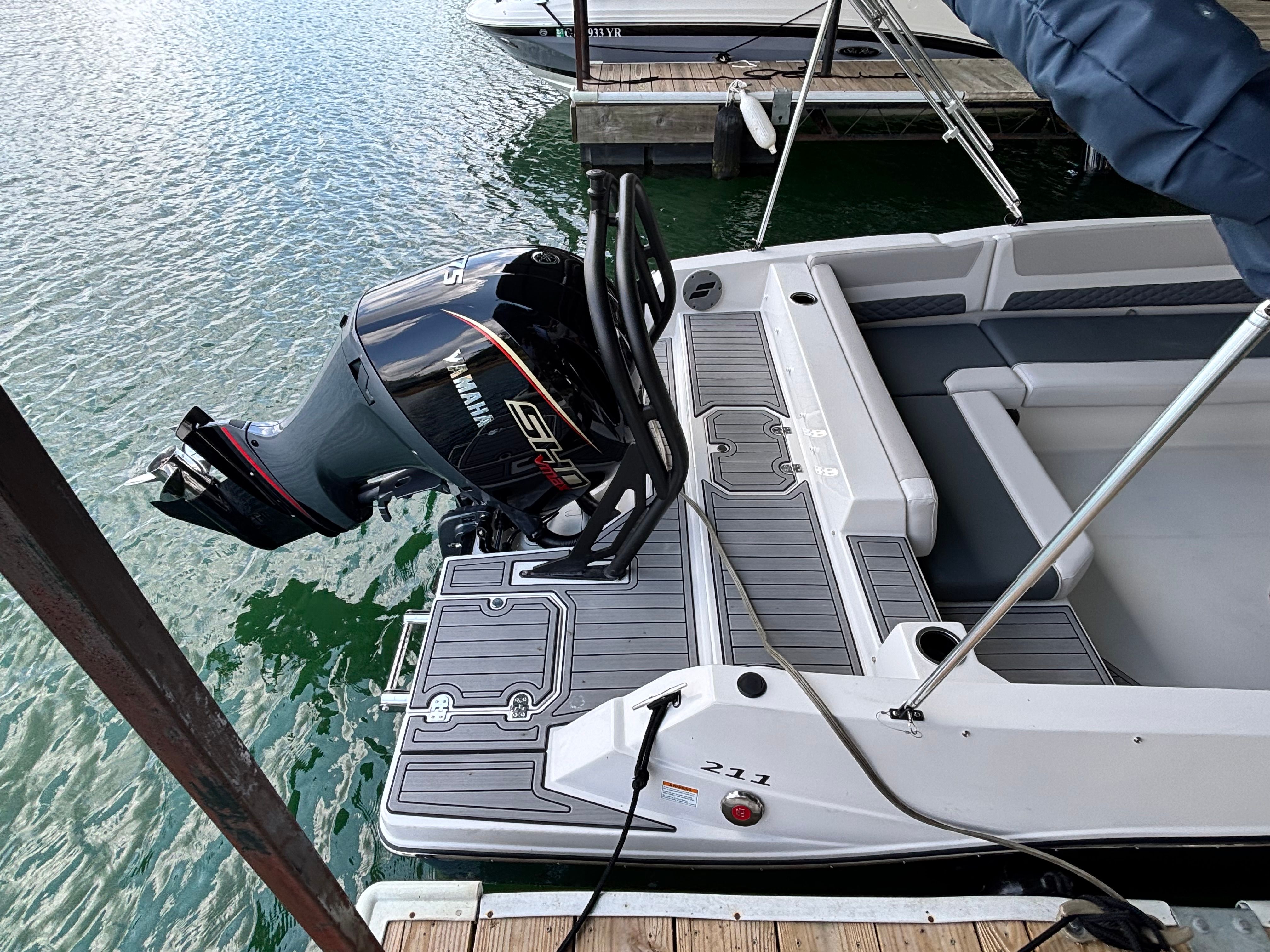 A 2027 Starcraft 211SVXOB boat docked. It features an outboard motor and gray upholstery.