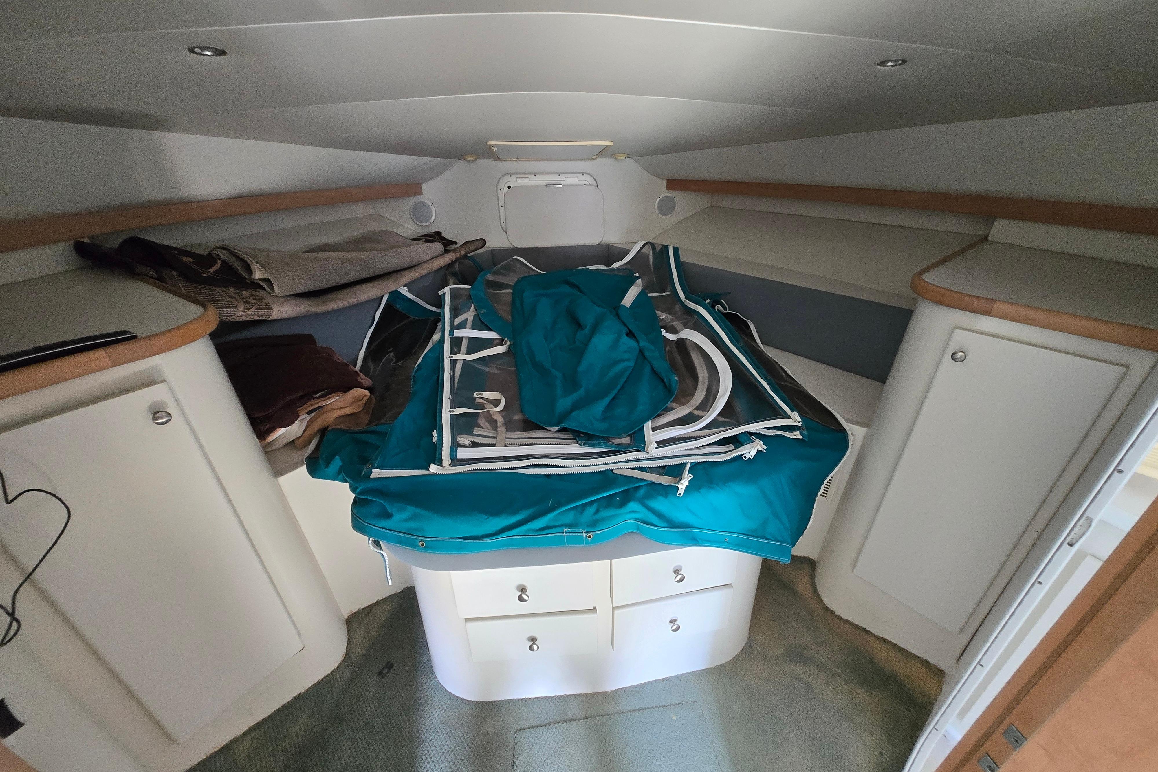 Interior cabin of a 1994 Carver 380 Santego boat with storage and teal covers.