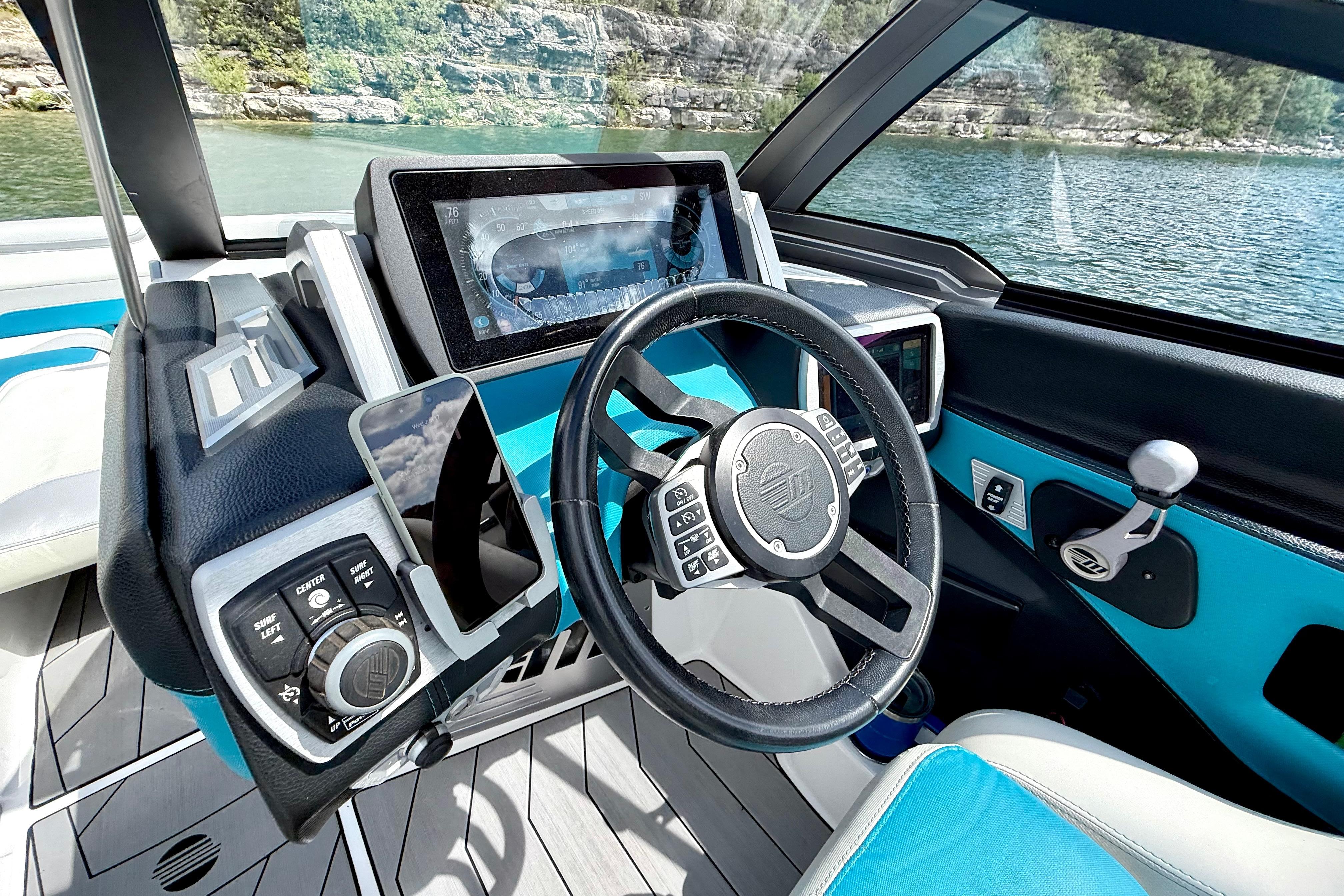 2017 Malibu M235 boat dashboard with modern controls and touchscreen display on a scenic lake.