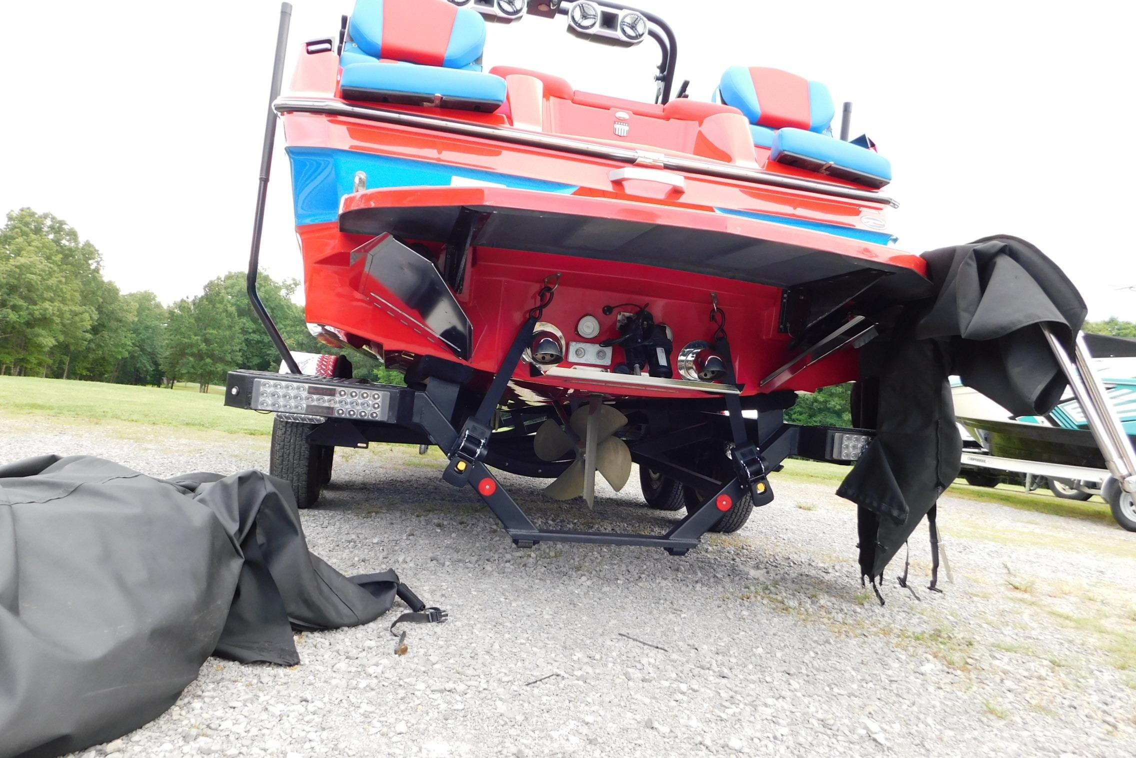 2022 MasterCraft NXT24 boat rear view with vibrant red and blue design on gravel.