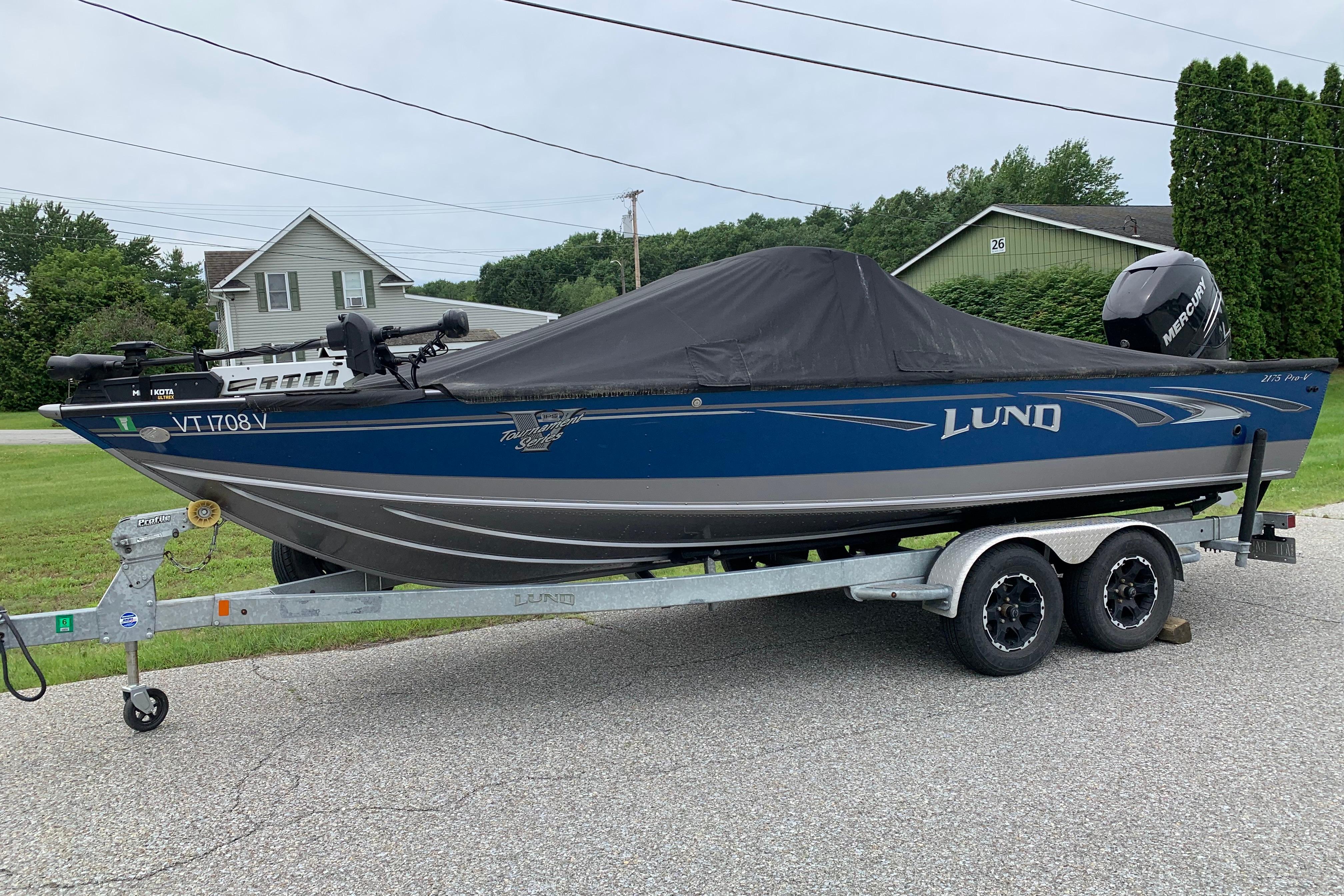 2019 Lund 2175 Pro-V boat on trailer, covered, parked in residential area.
