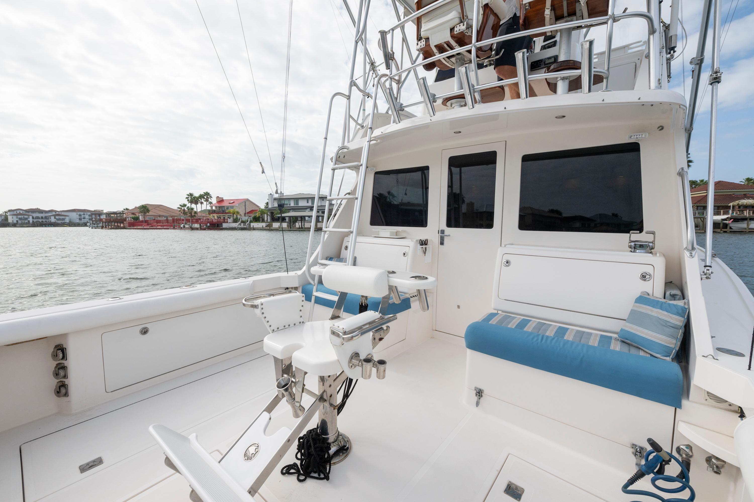 2005 Cabo 35 Flybridge boat deck with seating and fishing chair, overlooking waterfront homes.
