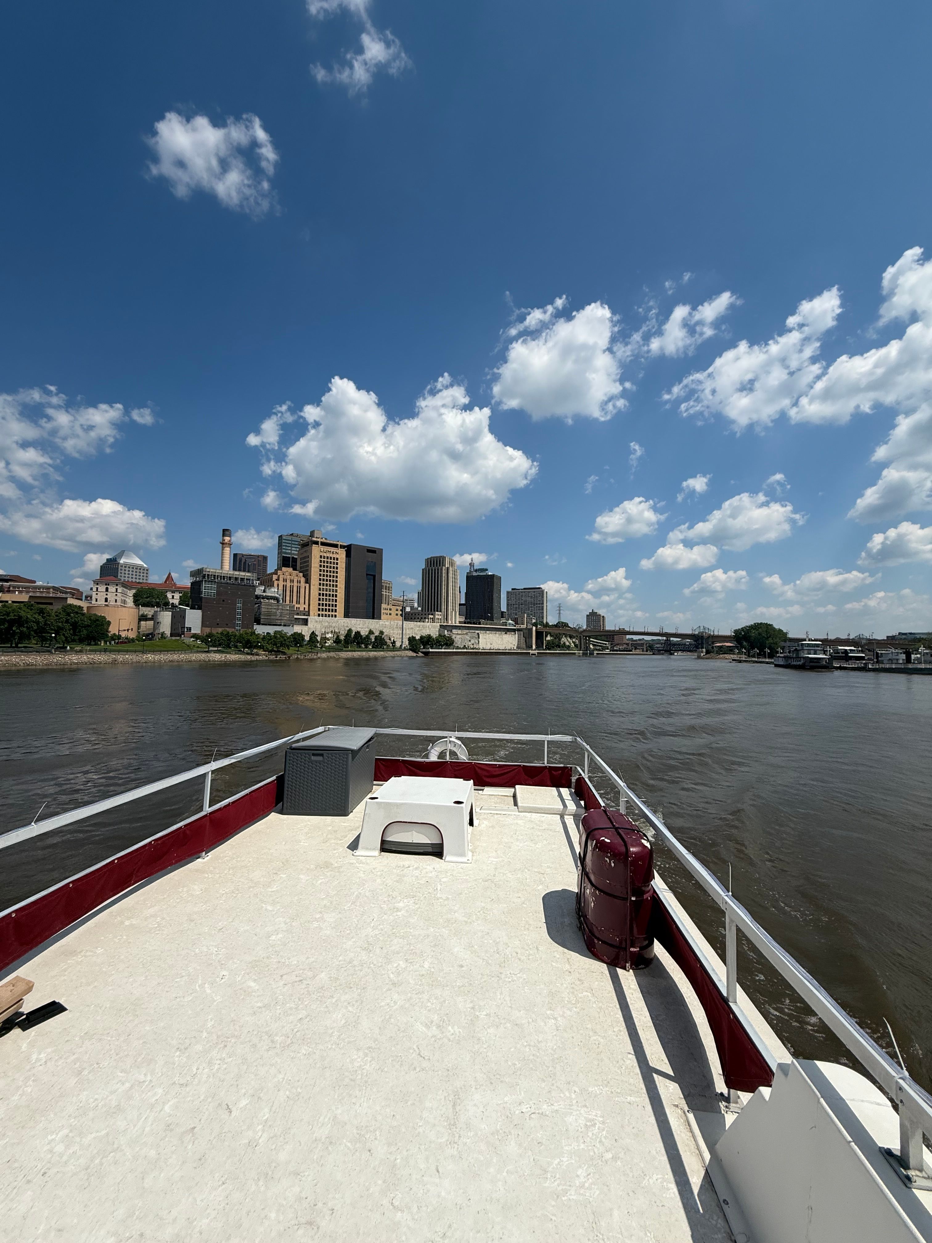 The boat is on a river with a city skyline in the background.