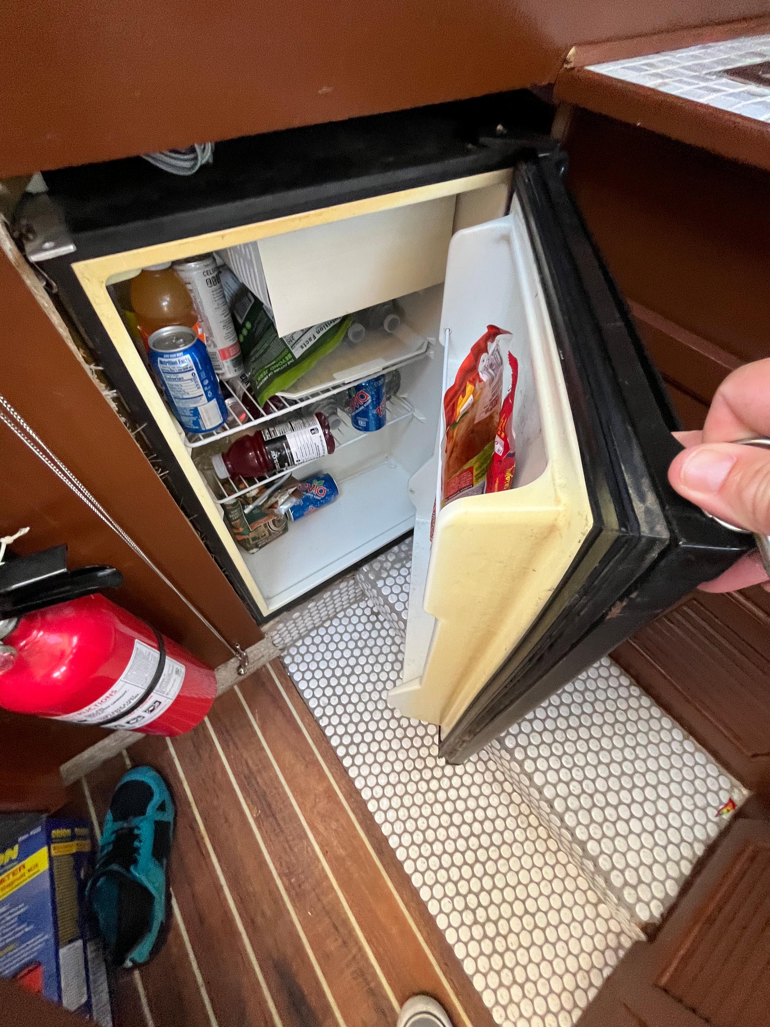 Open fridge in 1987 Scand Baltic boat with drinks and snacks inside.