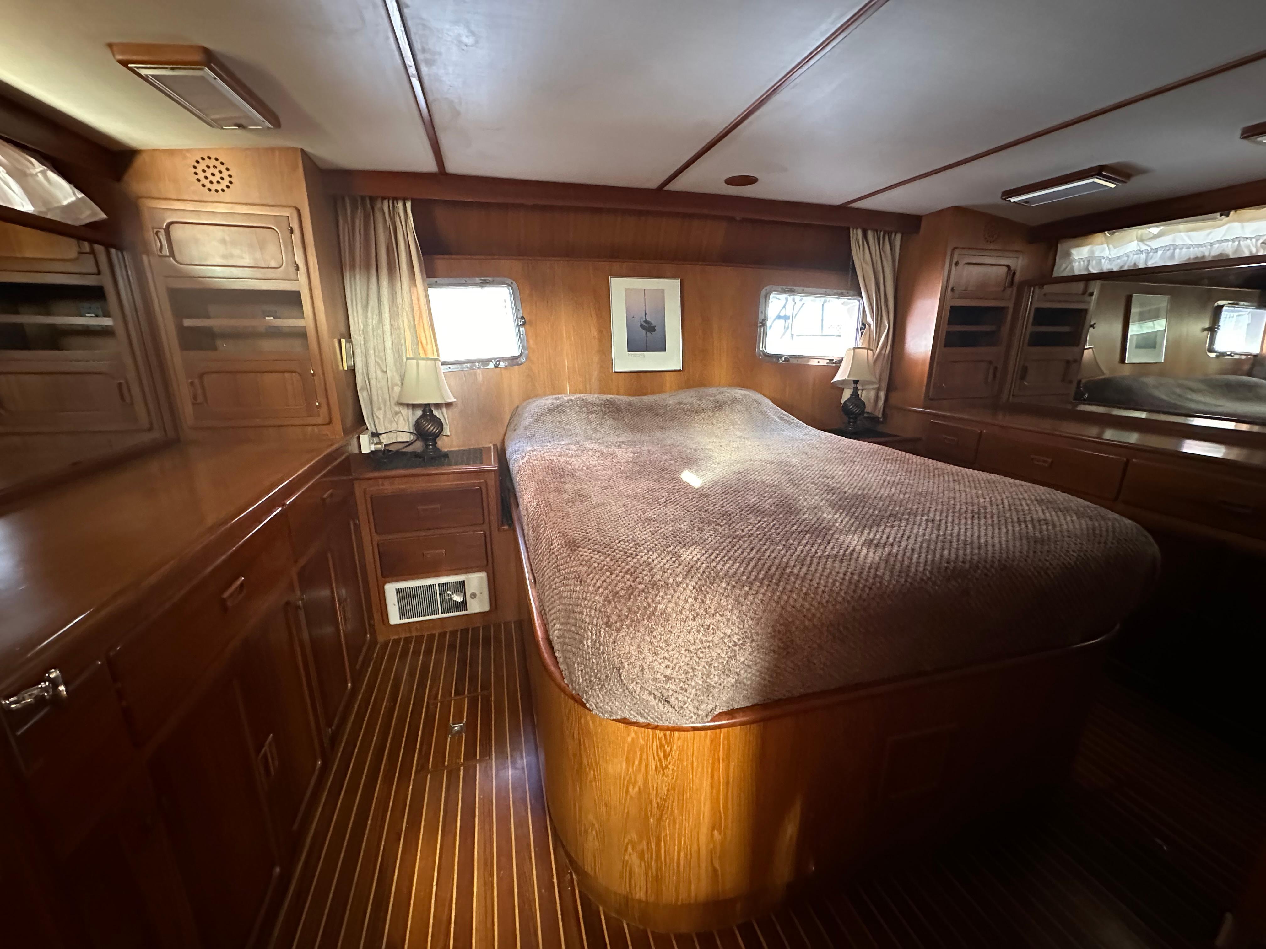 Luxurious wood-paneled bedroom in 1988 Vista 43 Motor Yacht with cozy bed and natural light.