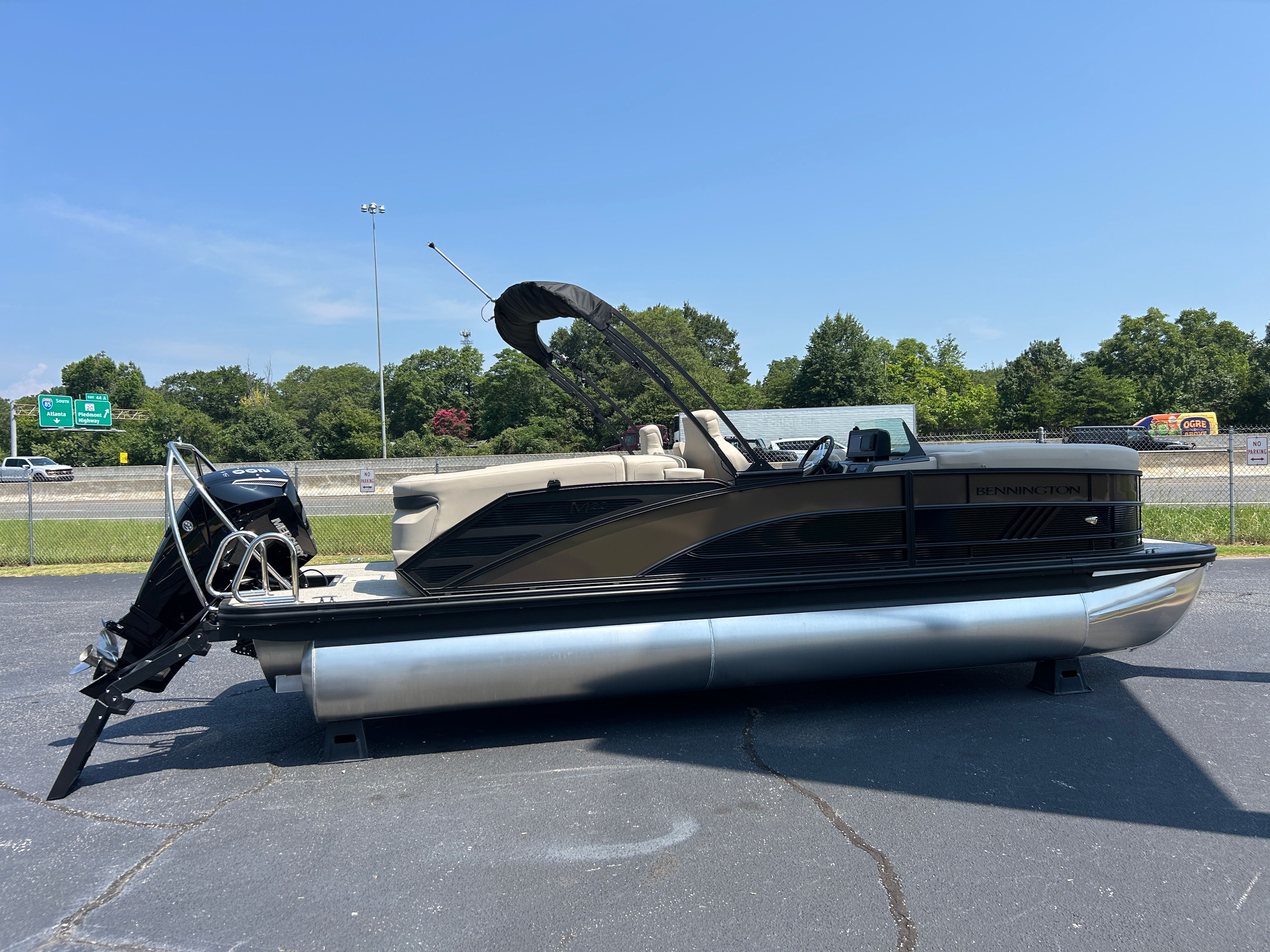 A Bennington 22 MFB pontoon boat is parked on a lot. It features a black canopy and silver pontoons.