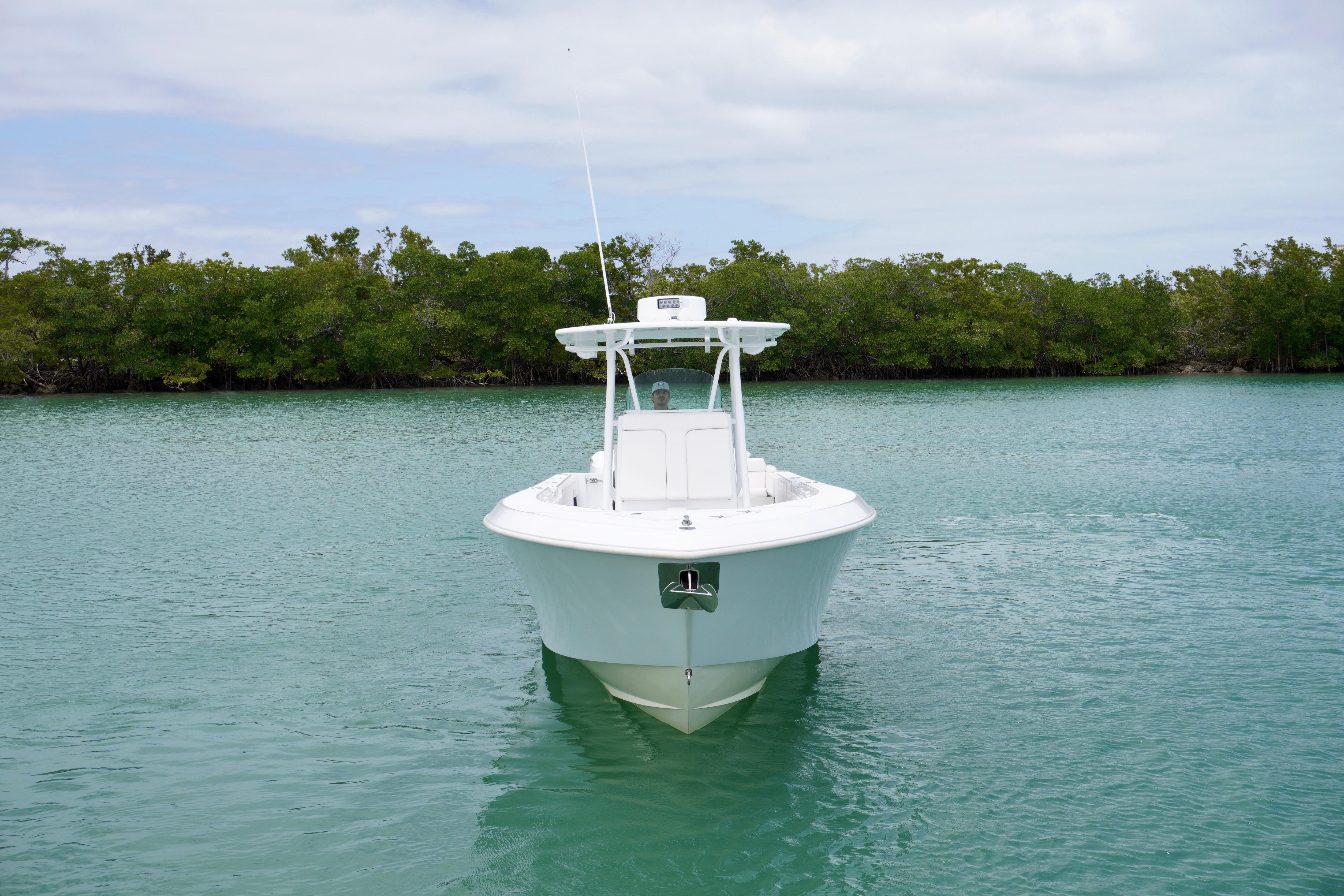 2013 Contender 35 LS boat on calm water with lush green shoreline.