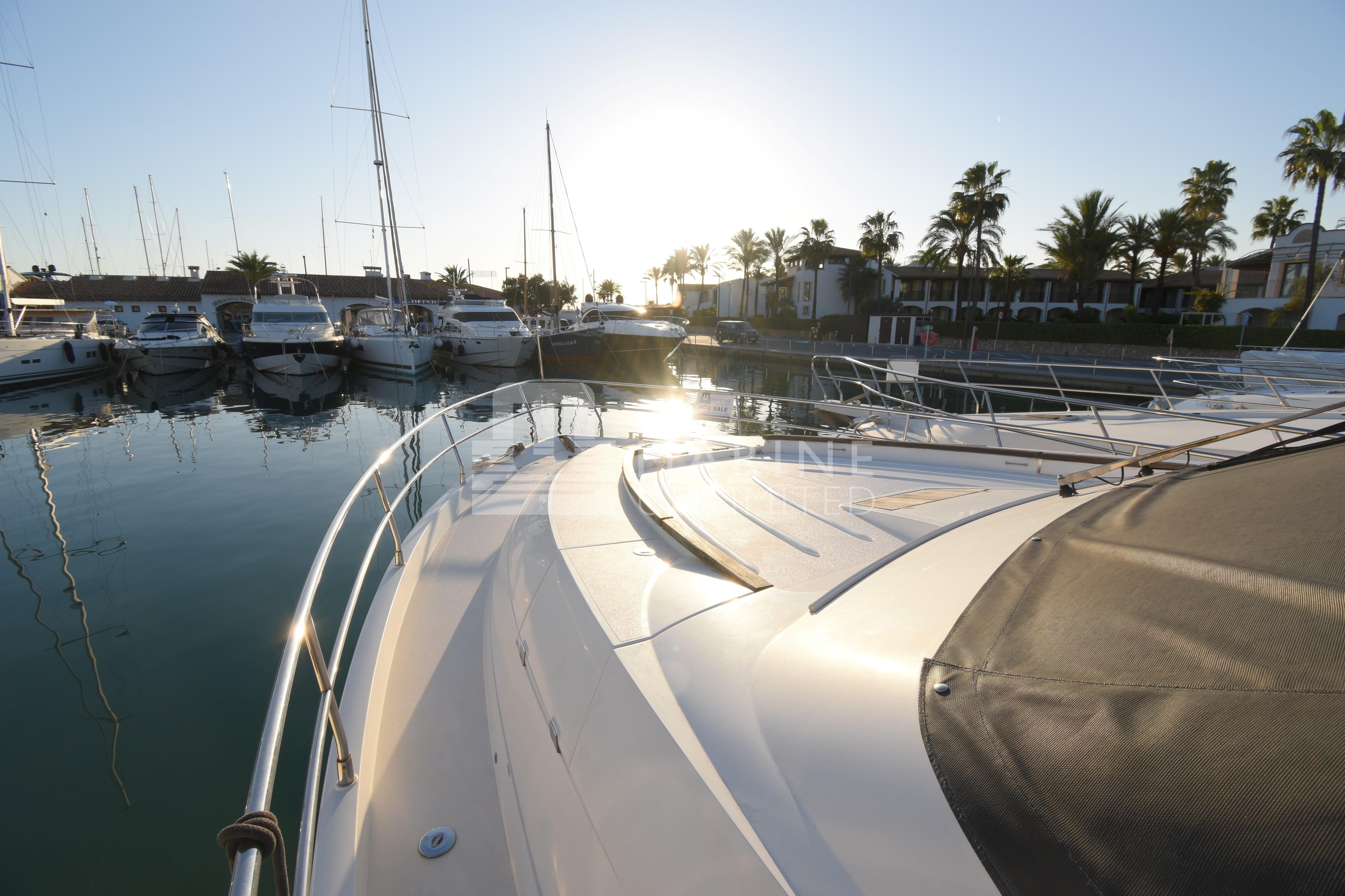 Luxurious 2010 Fairline Squadron 55 yacht docked at a serene marina during sunset.