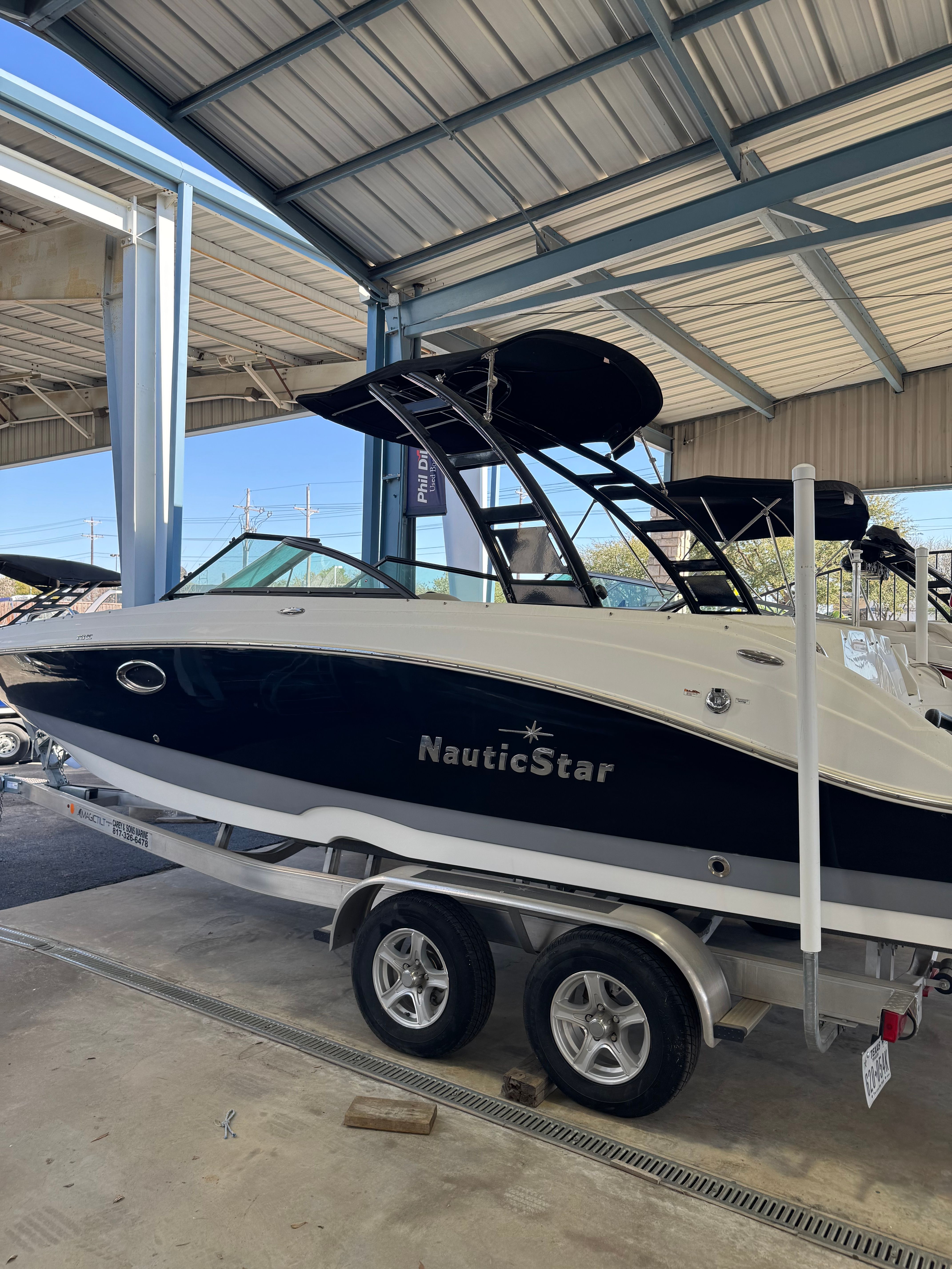 A 2021 NauticStar 243 DC boat on a trailer in a covered area.