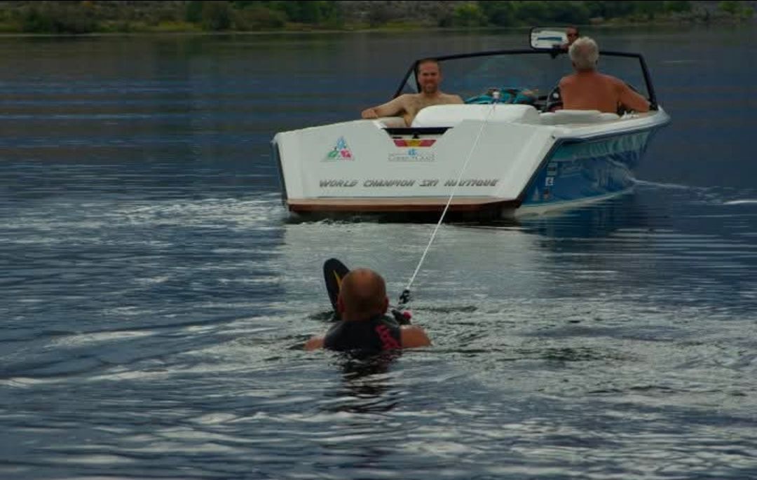 A water skier is being towed by a Correct Craft Sea Nautique boat.