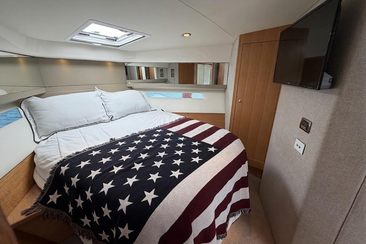 Luxurious bedroom in 2015 Riviera 445 SUV yacht with American flag blanket.