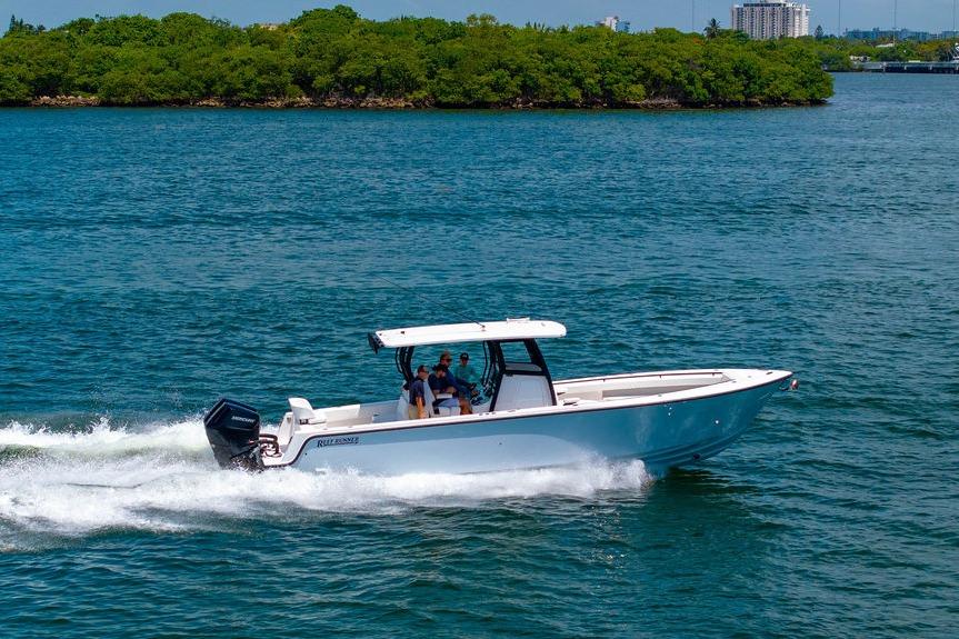 2027 Reef Runner 340 boat cruising on blue water near lush green island.
