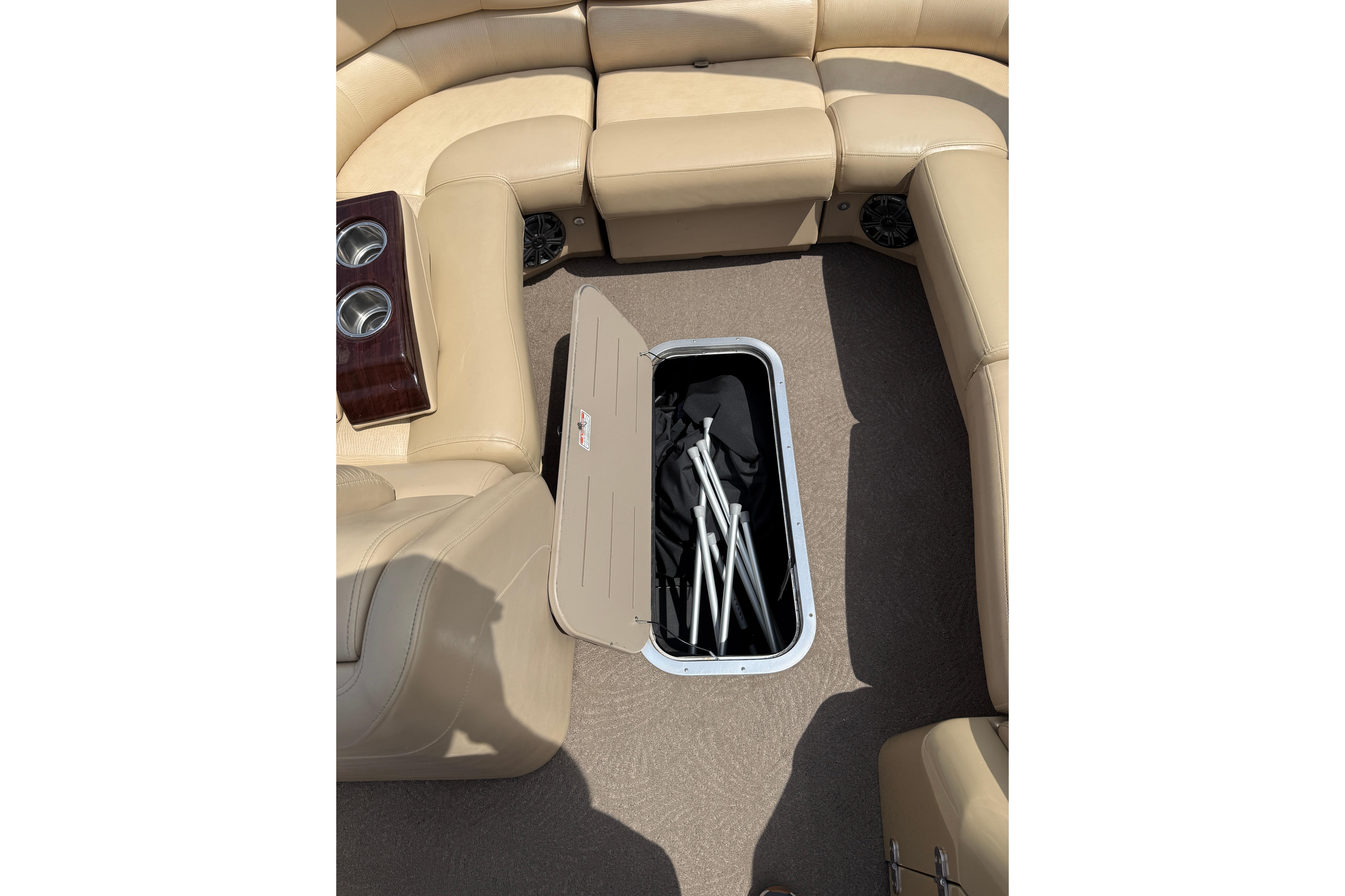 2011 Bennington 2575QCW I/O boat interior with open storage compartment and beige seating.
