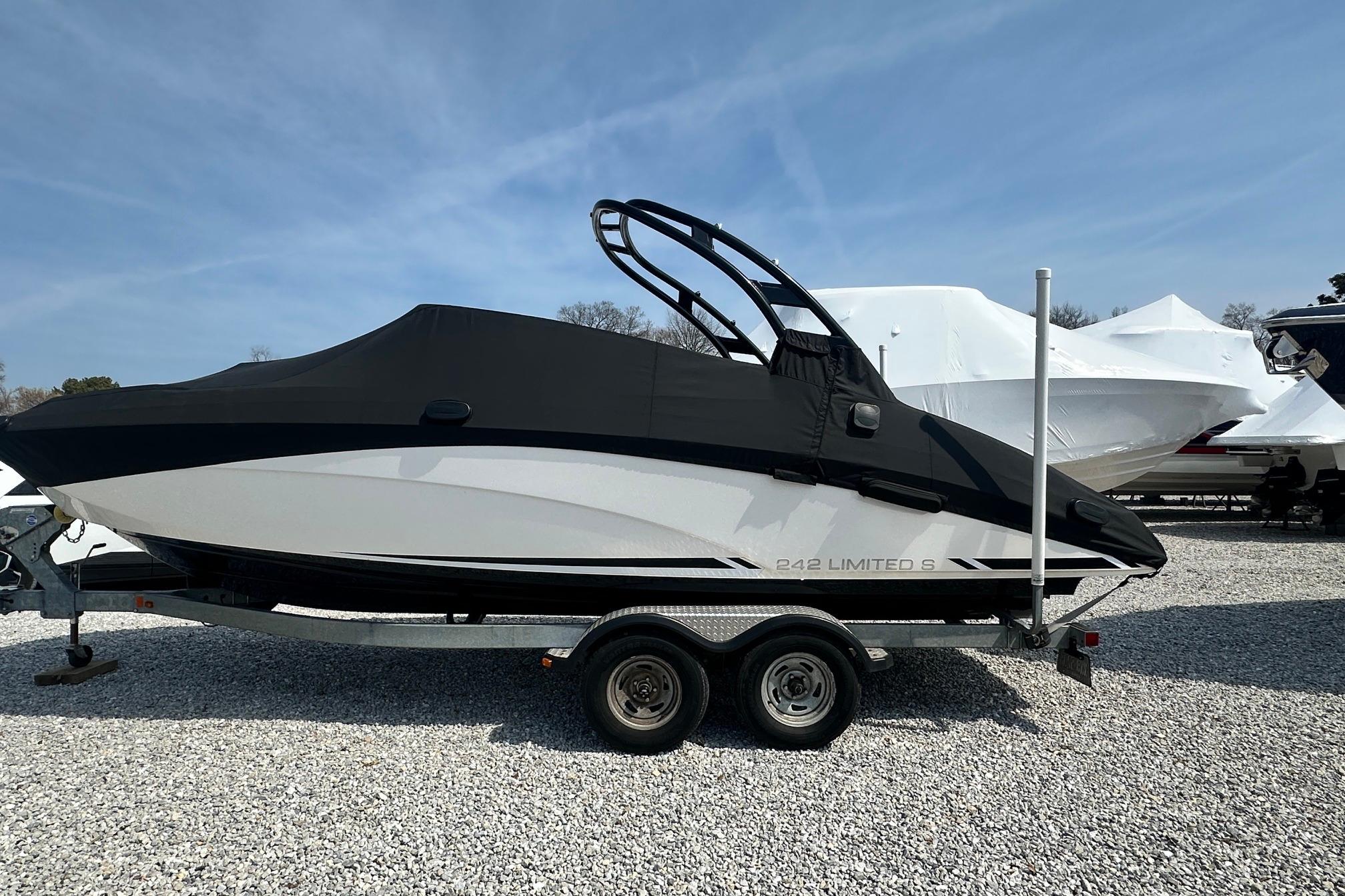 2016 Yamaha 242 Limited S boat on trailer, covered, parked on gravel lot.