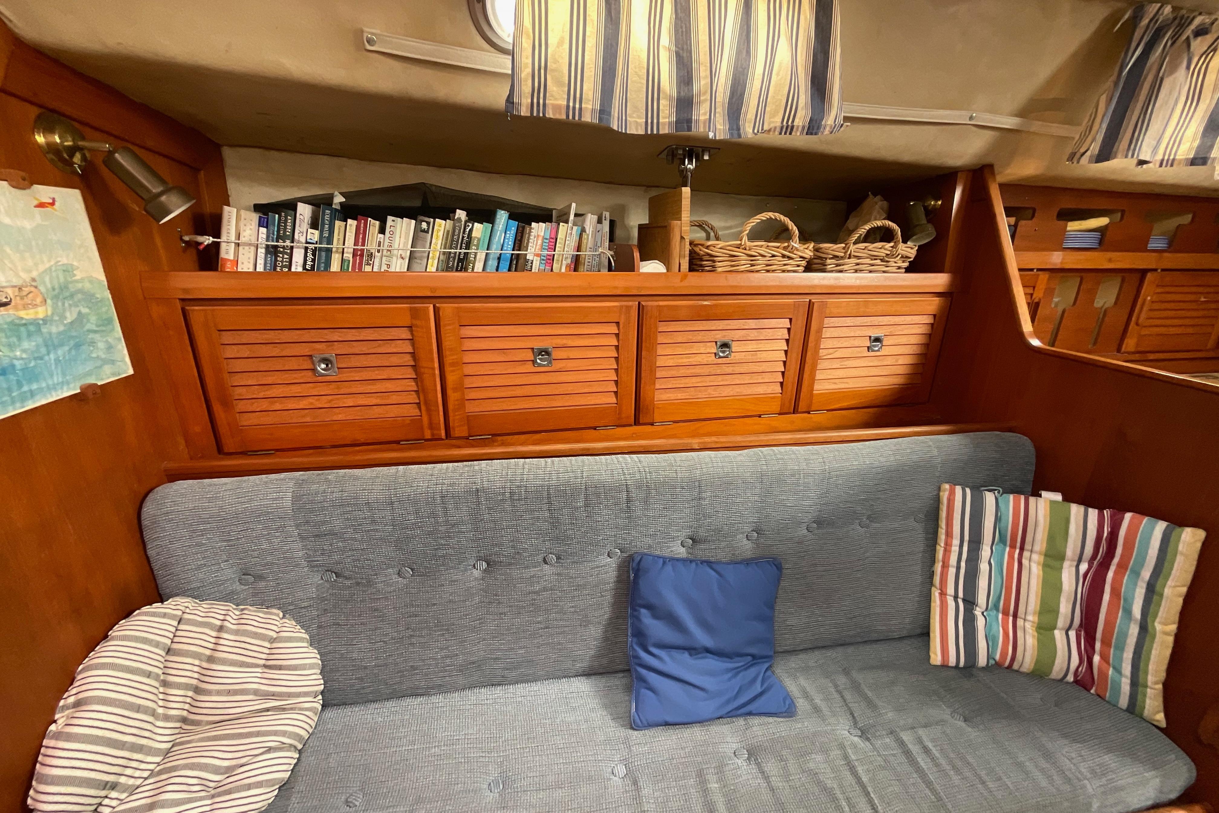 Cozy interior of 1988 Westerly Corsair 36 sailboat with bookshelves and cushions.