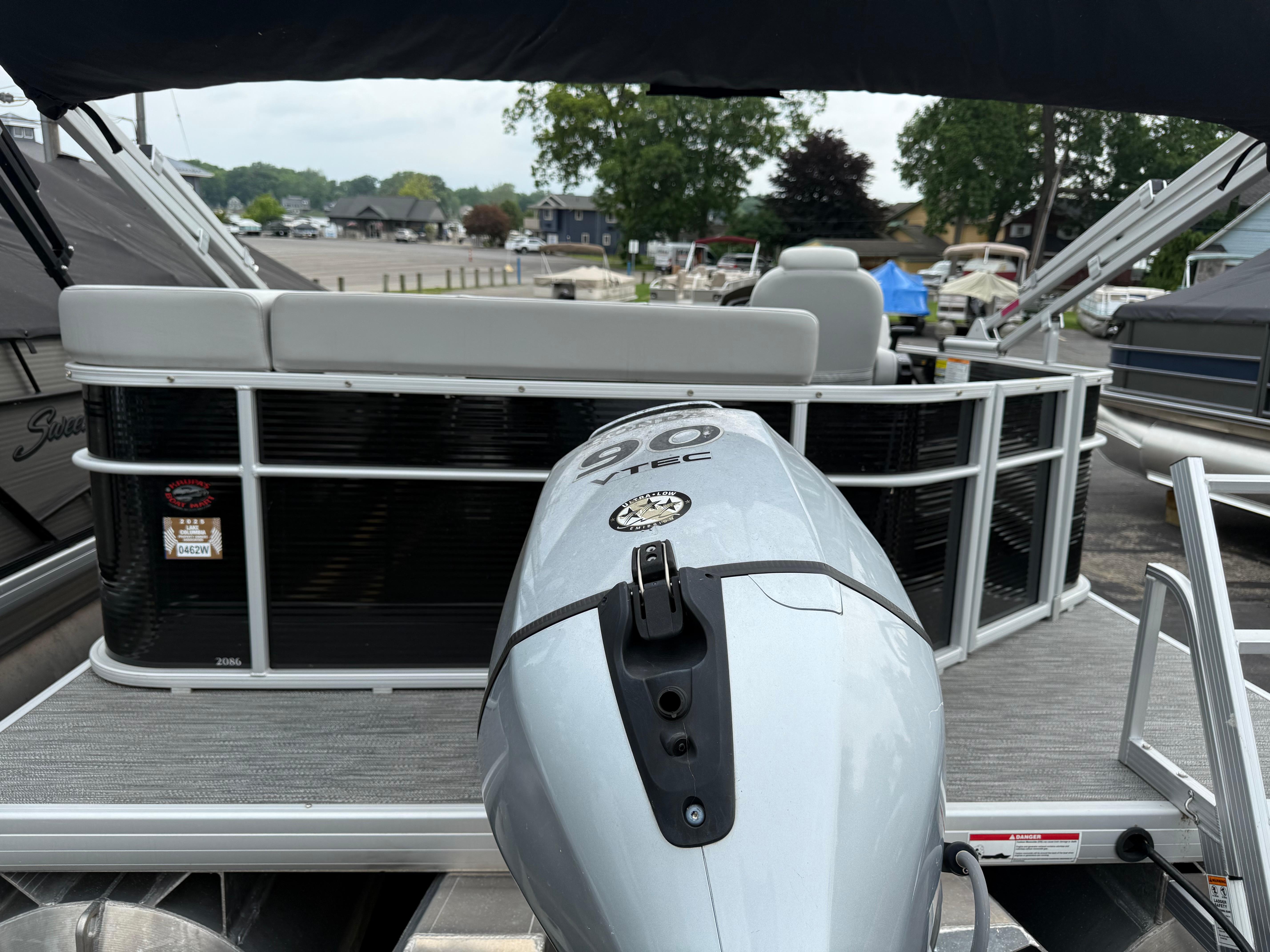 2023 Godfrey Sweetwater pontoon boat with outboard motor, docked at marina.