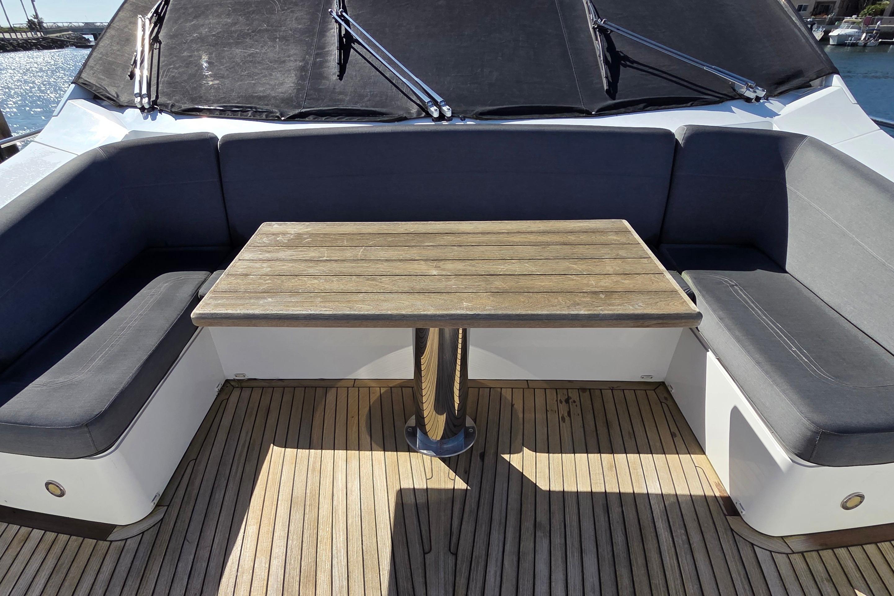 Luxurious seating area on 2018 Sunseeker 76 Yacht with wooden table and cushioned benches.