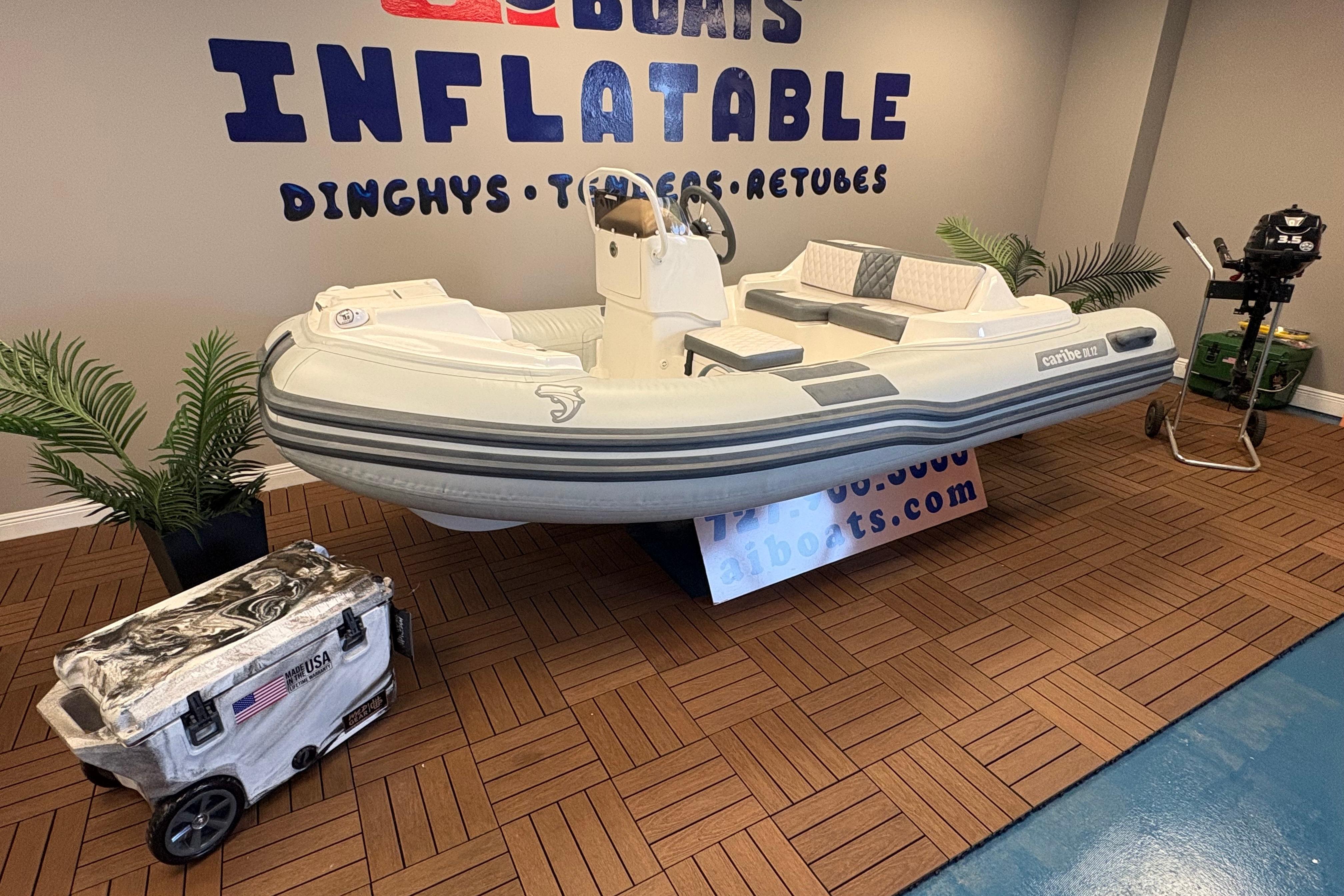 Inflatable Caribe DL12 boat, 2026 model, displayed indoors with accessories and promotional signage.