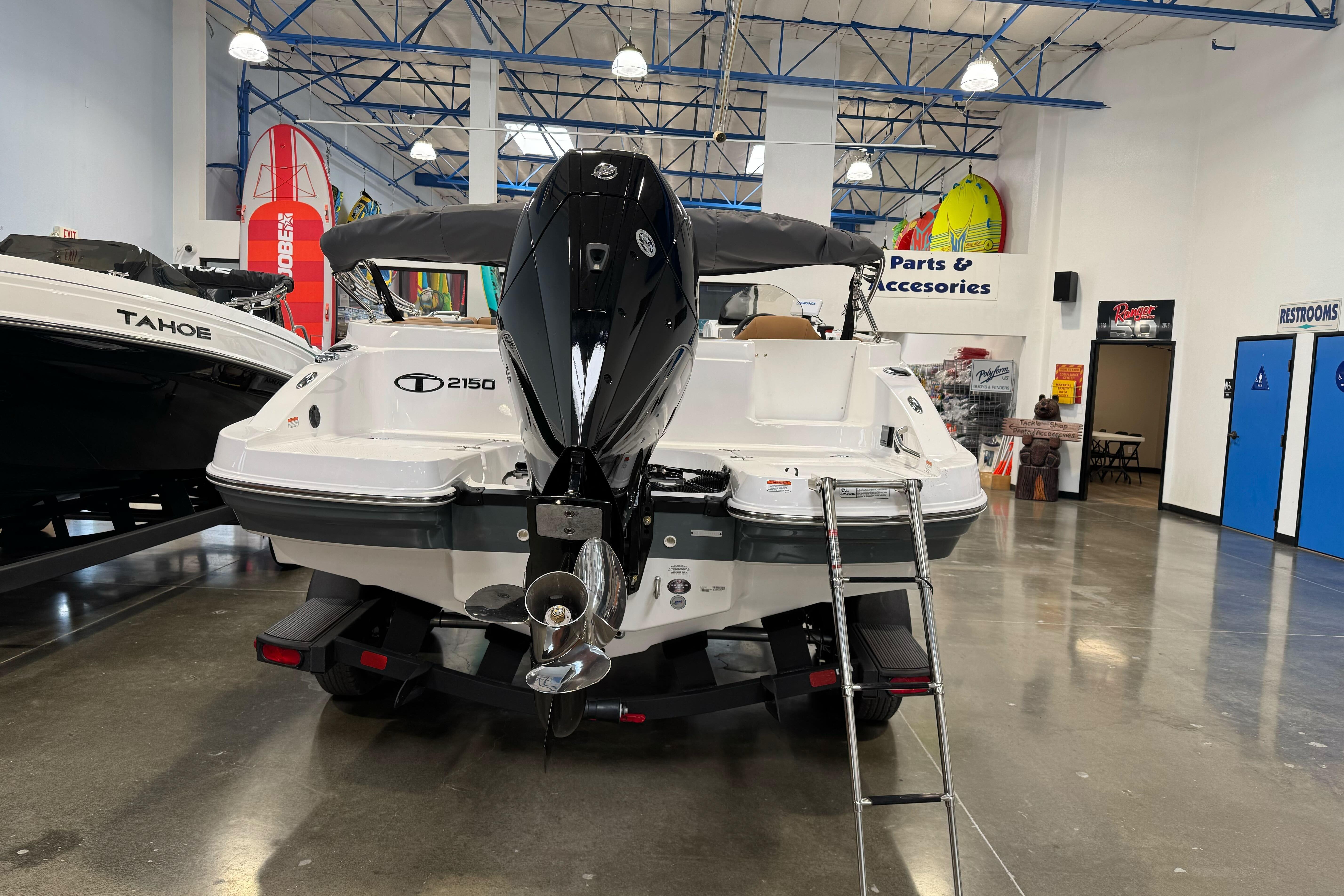2026 Tahoe 2150 boat displayed indoors with outboard motor and ladder.