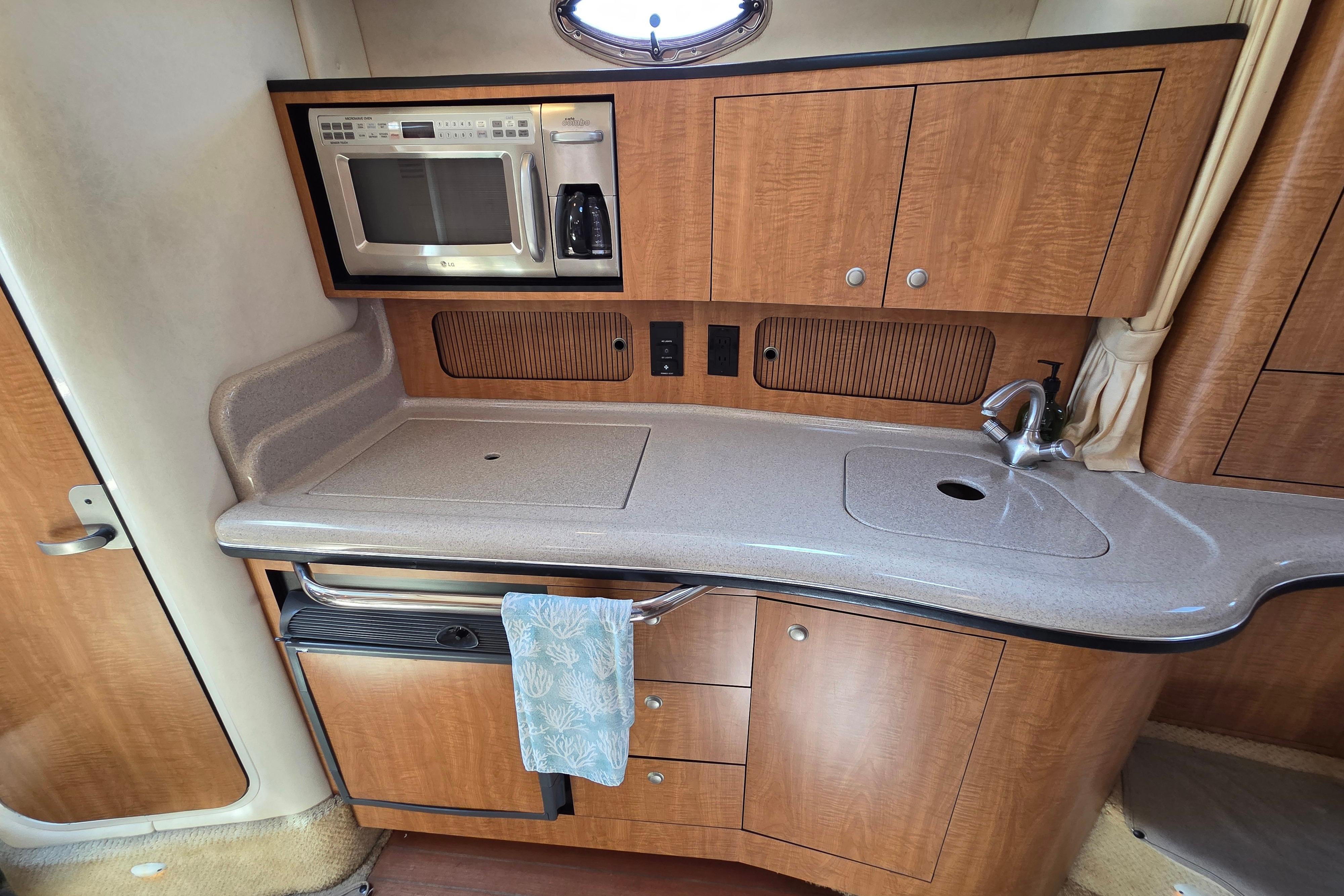 2006 Sea Ray Sundancer 320 galley with microwave, sink, and wooden cabinetry.