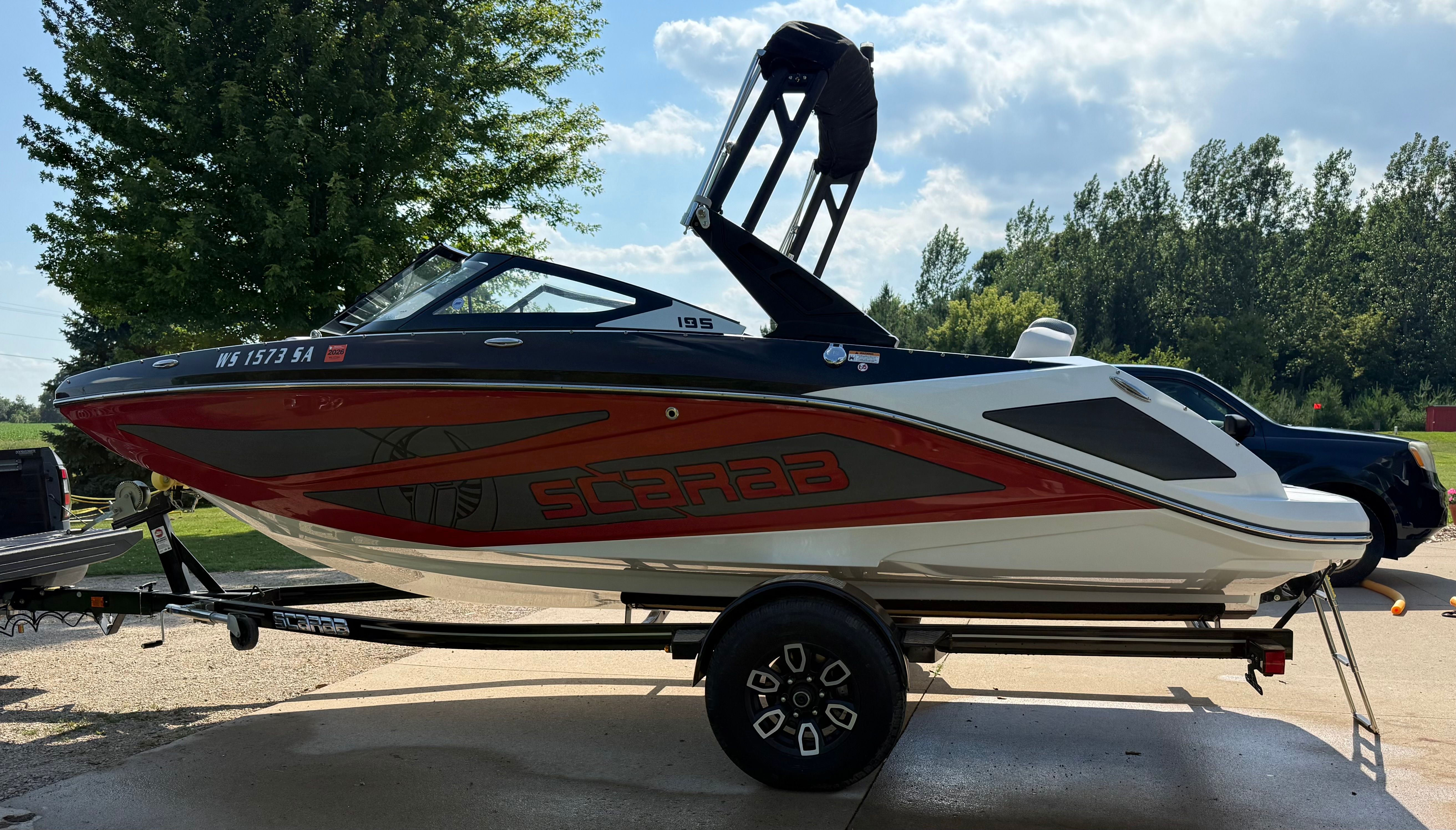 A 2023 Scarab 195 ID boat on a trailer, featuring a sporty design with red accents.