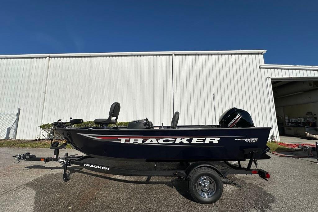 2026 Tracker Pro Guide V-16 SC boat on trailer, parked outside a white building.