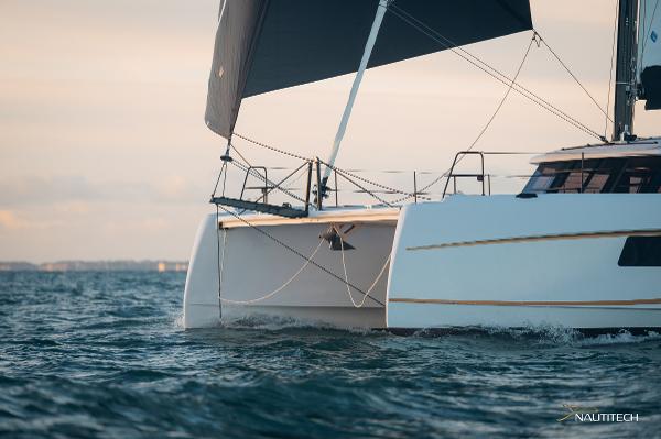 2025 Nautitech 48 Open catamaran sailing on the ocean at sunset.