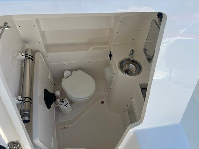 Interior view of a boat cabin with a toilet, sink, and storage space.