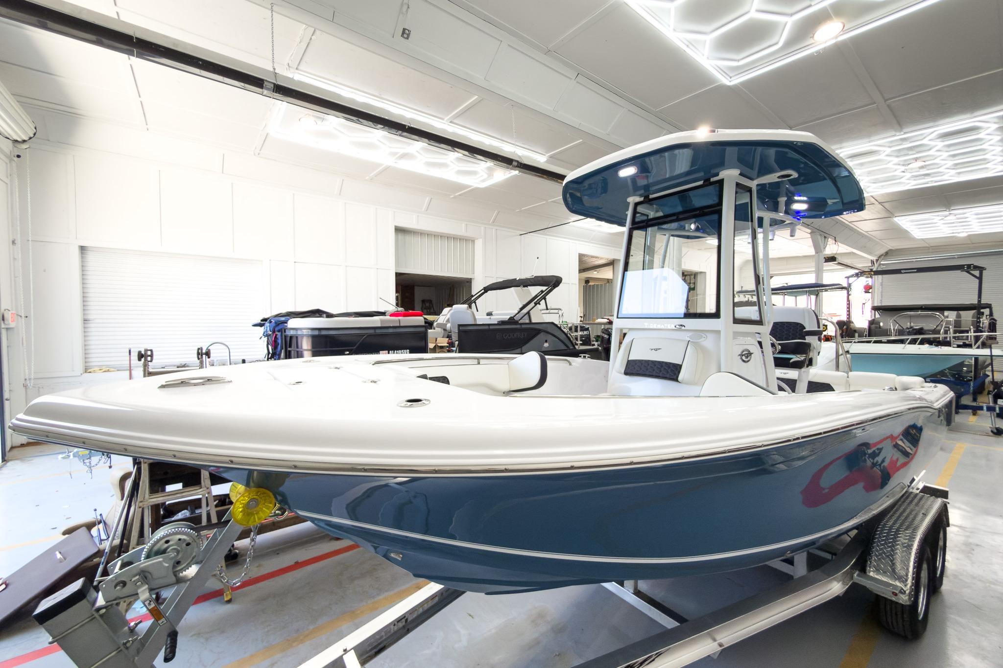 The 2026 Tidewater 220 LXF is in a modern showroom. It features a blue hull design.