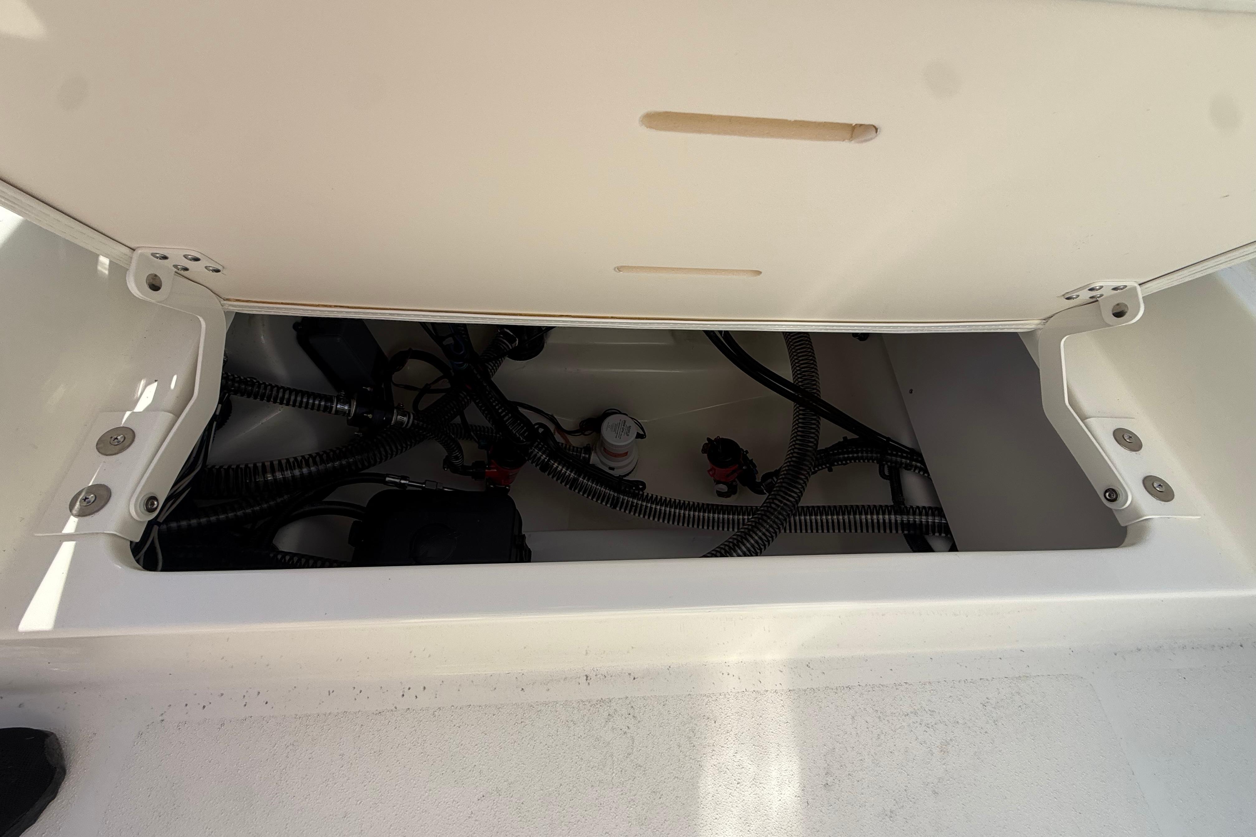 Open storage compartment of 2026 Mako 24 APEX boat, showing internal wiring and components.