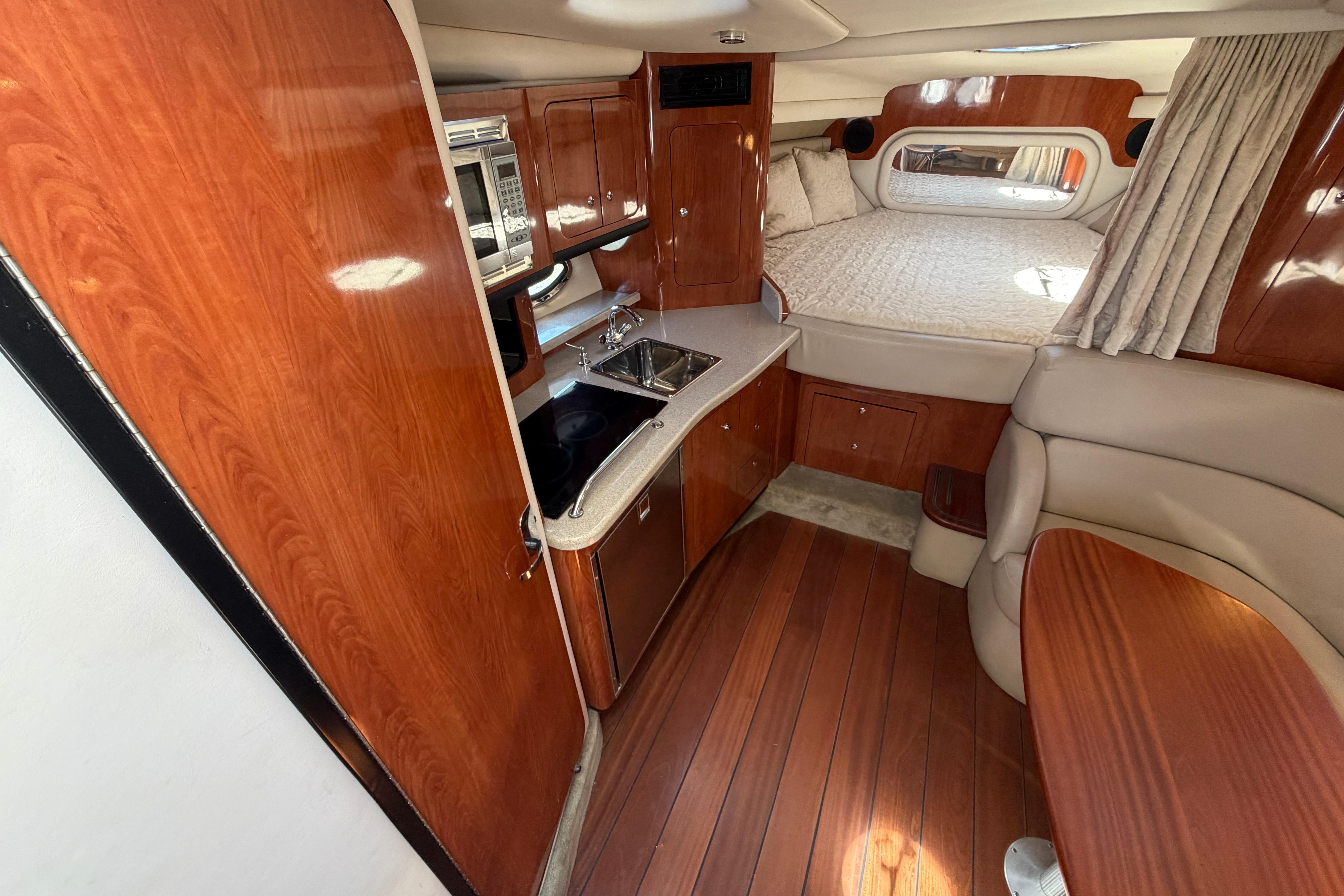 2008 Crownline 340 CR cabin interior with wood finish, kitchenette, and cozy sleeping area.
