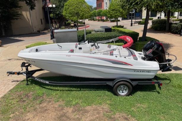 2024 Tahoe T18 boat on trailer, parked outdoors in a sunny urban setting.