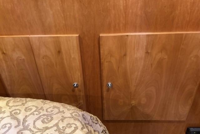 Wooden cabinet doors in a 2007 Navigator 5100 interior, next to patterned bedding.