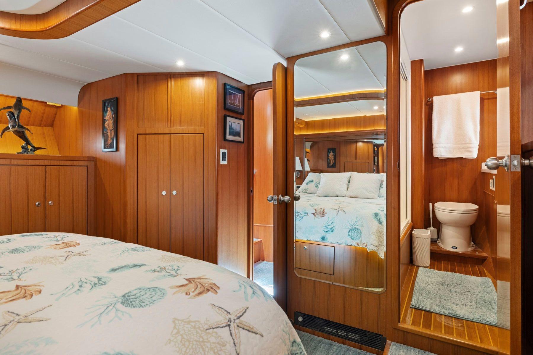 Luxurious 1999 Symbol 55 yacht bedroom with ensuite bathroom, featuring elegant wood paneling.