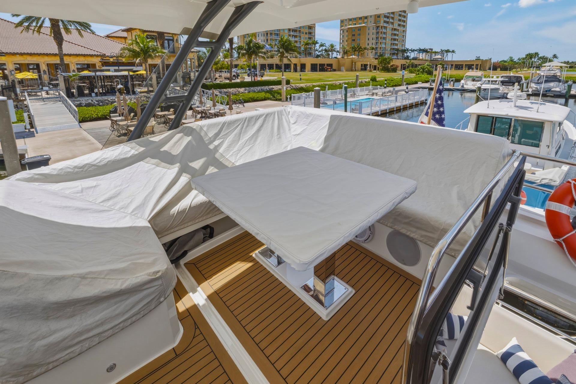 Cozy seating area on 2022 Prestige 520 yacht, docked at a sunny marina.