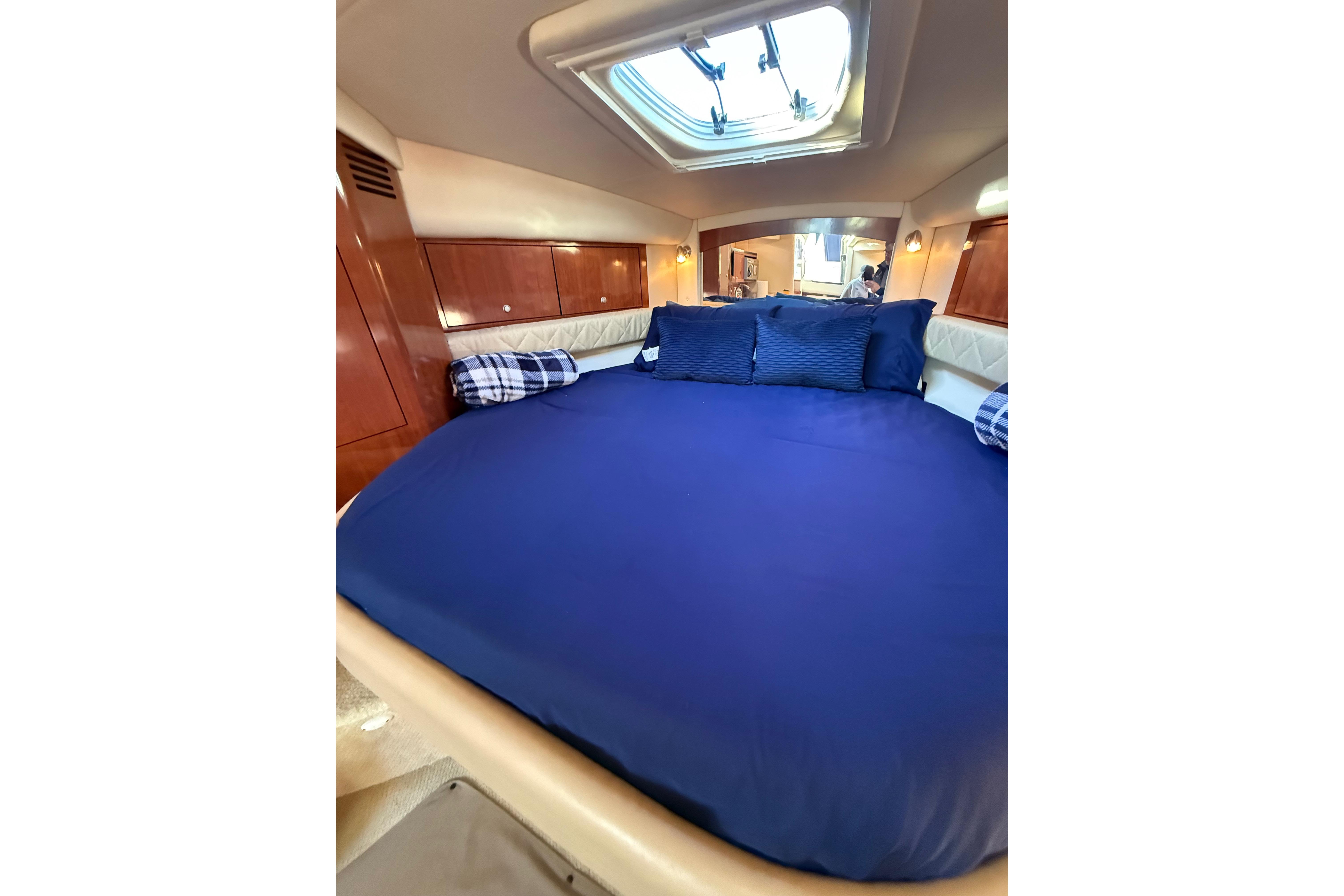 Luxurious cabin interior of 2007 Sea Ray 340 yacht with blue bedding and wood accents.