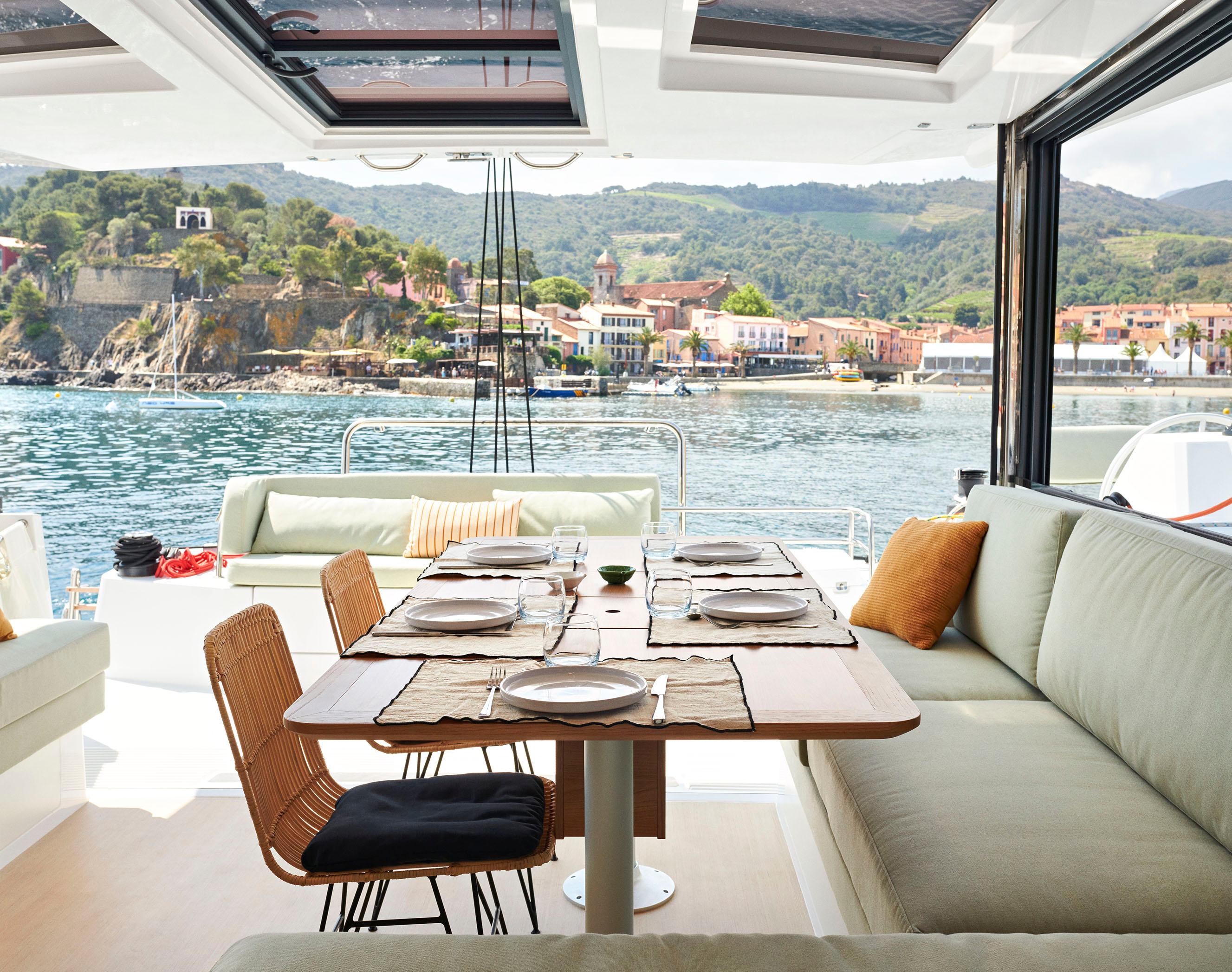 Luxurious Bali CATSMART 2026 yacht interior with elegant dining setup, scenic coastal view.