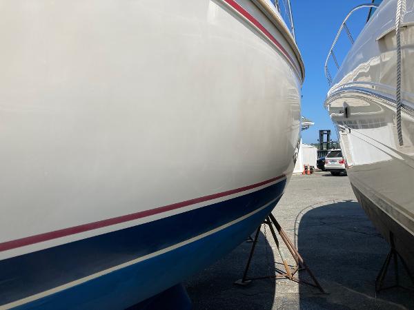 1989 Catalina 30 sailboat hulls on stands in a marina under clear blue sky.