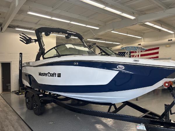 2025 MasterCraft XT22 boat in showroom, blue and white design, on trailer.
