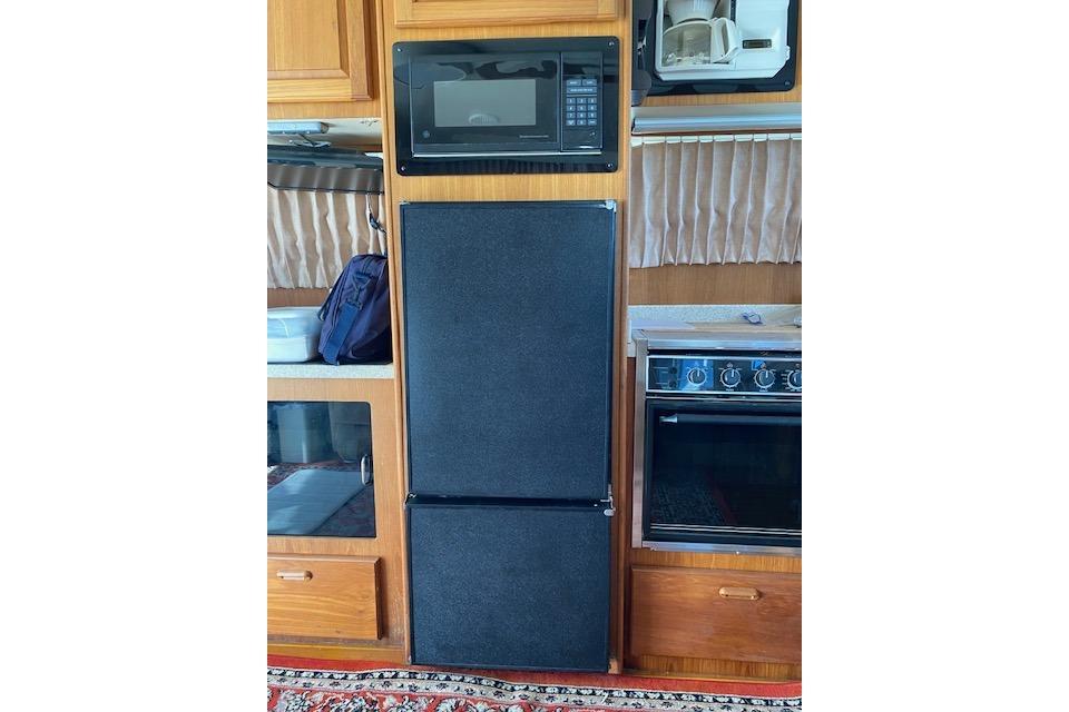 1999 Mainship 350 Trawler kitchen with microwave, fridge, and stove.