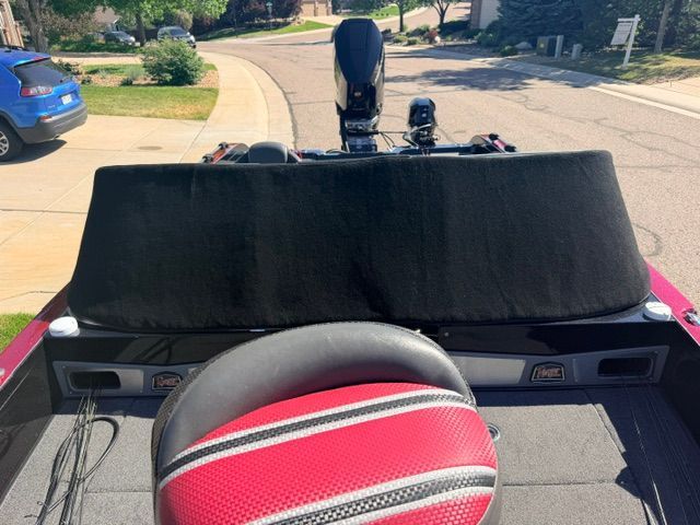 Ranger 621FS Pro 2024: Red and black boat with padded seat, parked on a street.