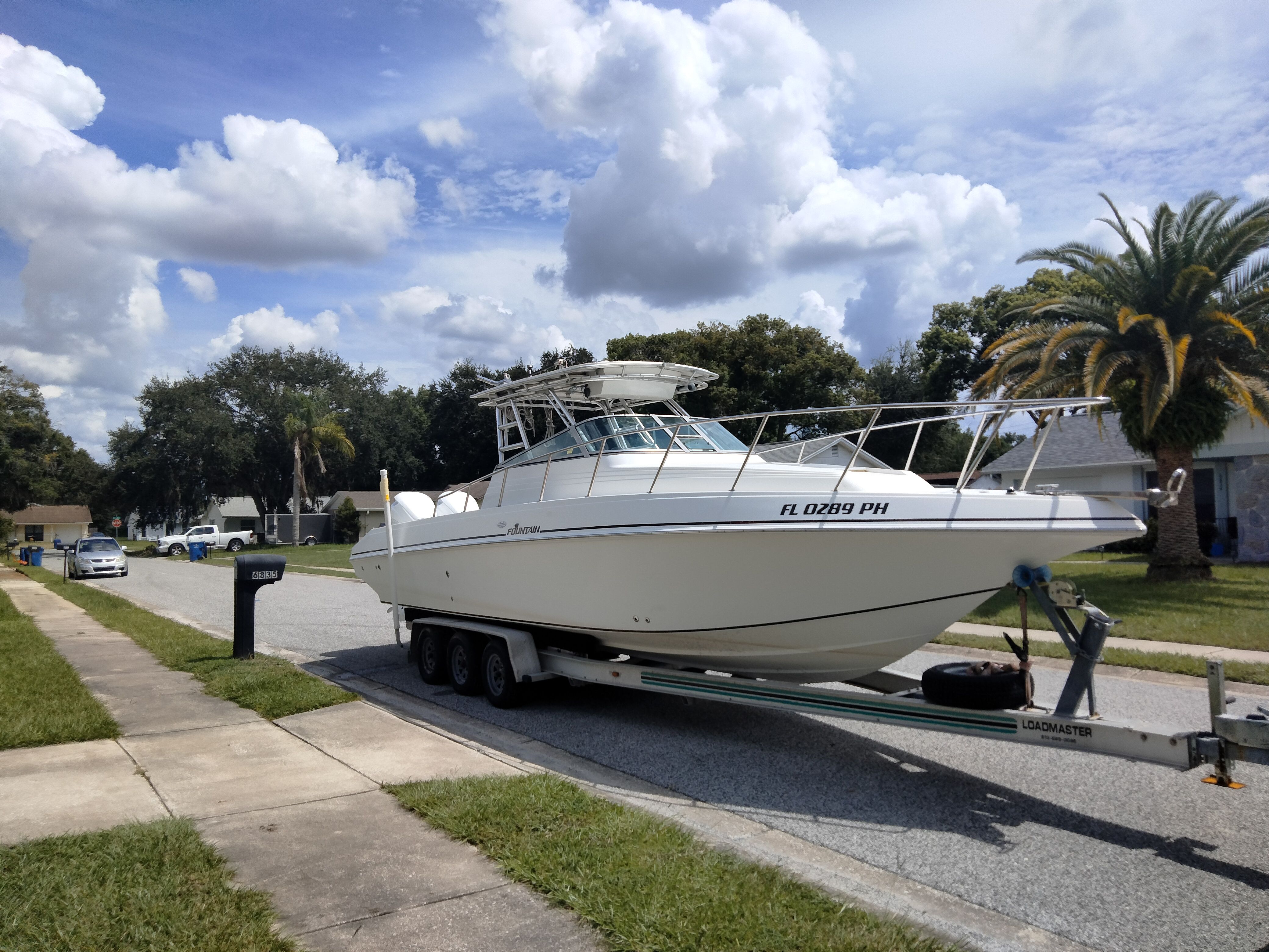 A 1995 Fountain 31 SFC boat on a trailer in a residential street.