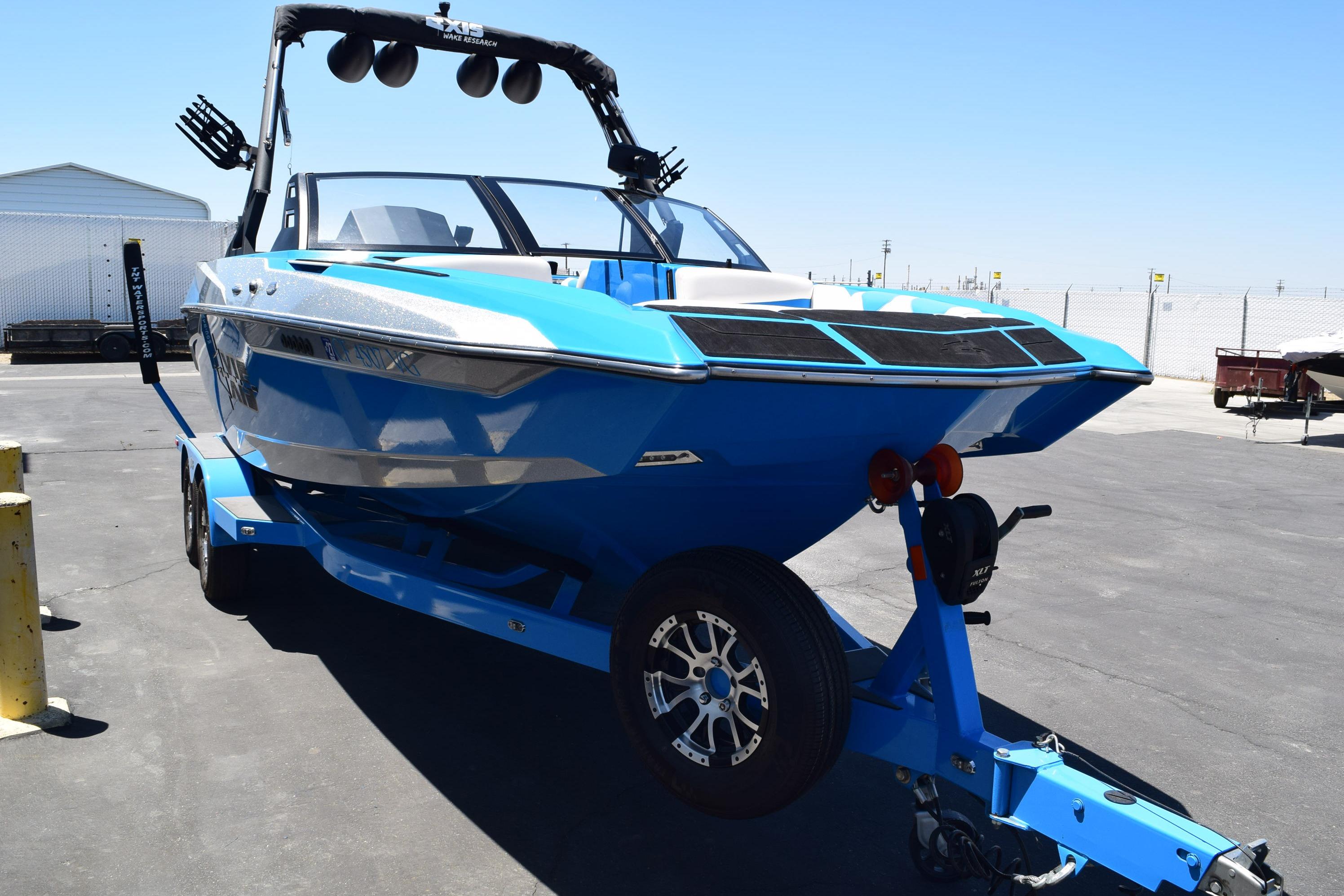 2019 Axis A22 boat in vibrant blue on a matching trailer, parked outdoors.