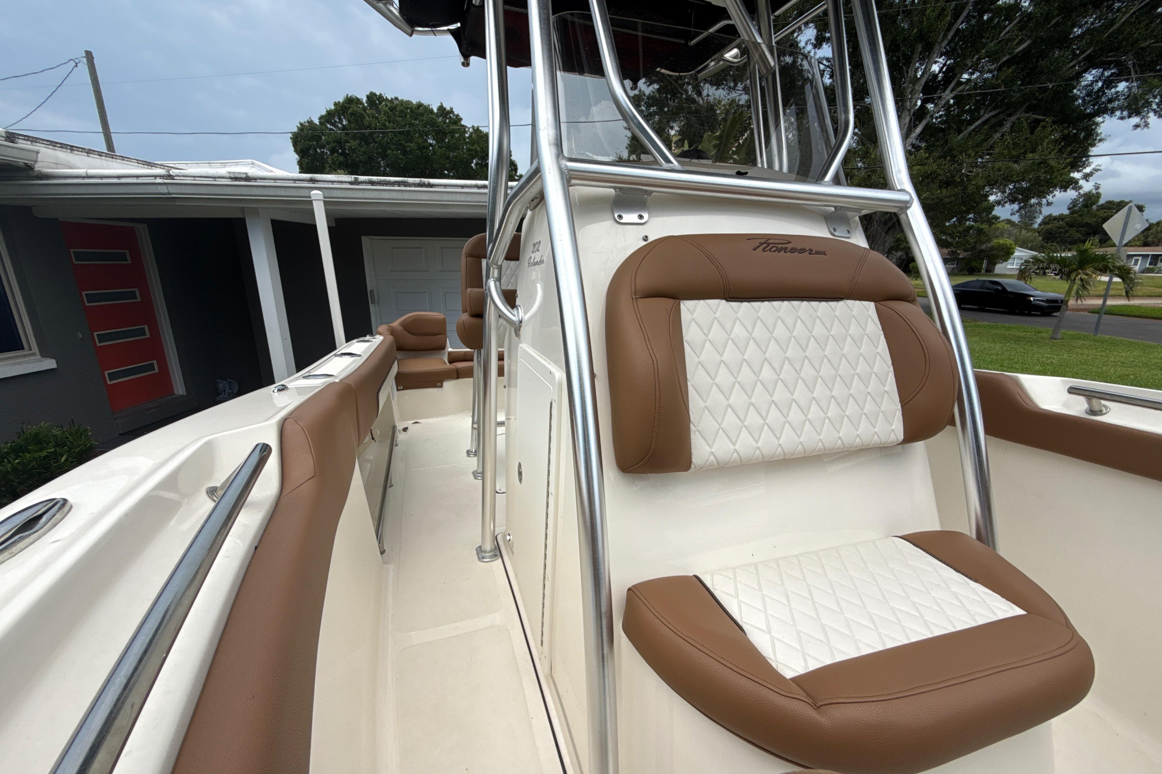 2023 Pioneer 202 Islander boat with brown and white seating, parked near a house.