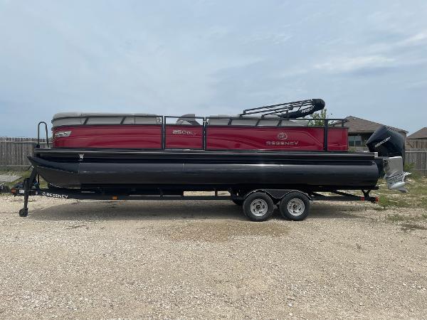 2023 Regency 250DL3 pontoon boat on trailer, red and black design, parked outdoors.