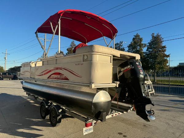 2005 Starcraft 22 Sport pontoon boat with red canopy and Suzuki outboard motor.